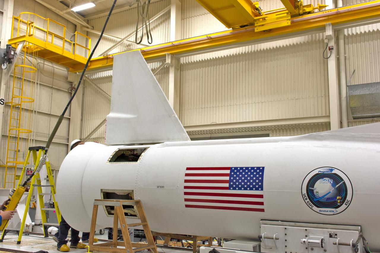 Inside Building 1555 at Vandenberg Air Force Base in California, technicians install the first of two fins on Northrop Grumman's Pegasus XL rocket on July 30, 2018. The Pegasus XL rocket, attached beneath the company's L-1011 Stargazer aircraft, will launch NASA's Ionospheric Connection Explorer (ICON) from the Skid Strip at Cape Canaveral Air Force Station in Florida. Launch is scheduled for Oct. 26. ICON will study the frontier of space - the dynamic zone high in Earth's atmosphere where terrestrial weather from below meets space weather above. The explorer will help determine the physics of Earth's space environment and pave the way for mitigating its effects on our technology, communications systems and society.