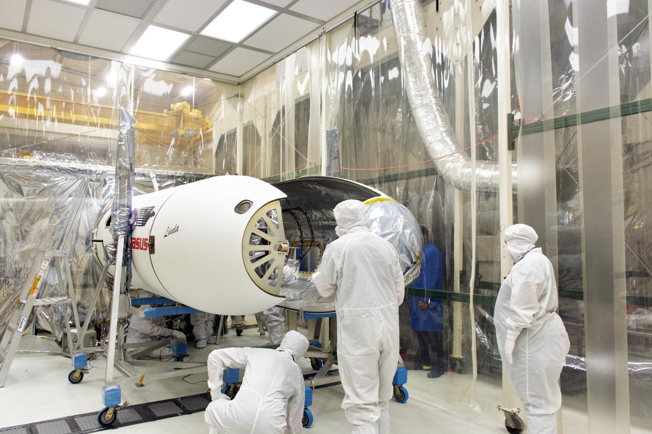 Technicians install the Northrop Grumman Pegasus XL payload fairings around NASA's Ionospheric Connection Explorer (ICON) inside Building 1555 at Vandenberg Air Force Base in California, on Aug. 22, 2018. The Pegasus XL rocket, attached beneath the company's L-1011 Stargazer aircraft, will launch ICON from the Skid Strip at Cape Canaveral Air Force Station in Florida. Launch is scheduled for Oct. 26. ICON will study the frontier of space - the dynamic zone high in Earth's atmosphere where terrestrial weather from below meets space weather above. The explorer will help determine the physics of Earth's space environment and pave the way for mitigating its effects on our technology and communications systems.
