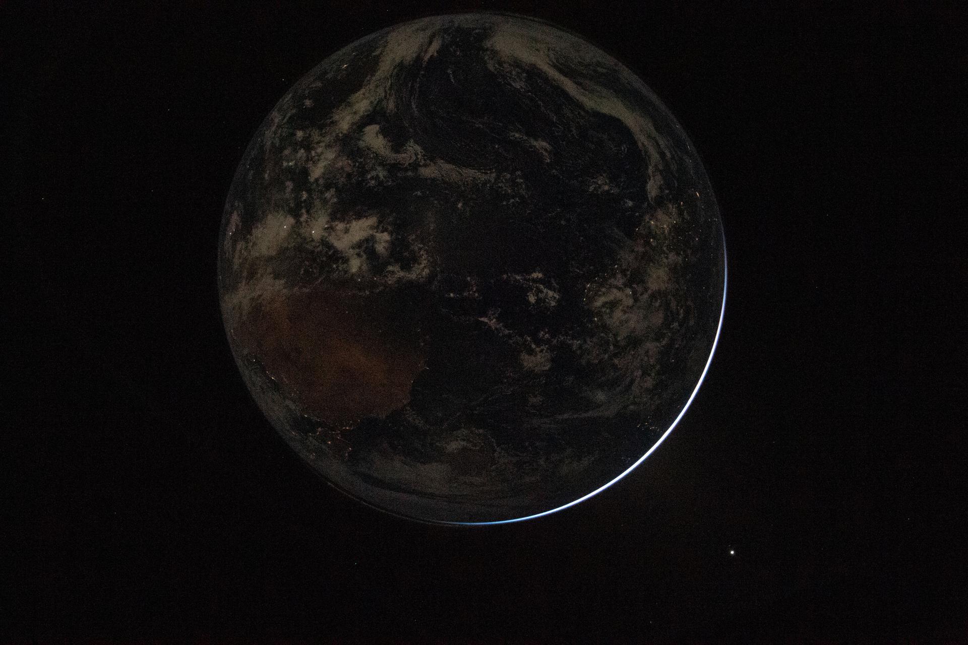 A view of a backlit Earth taken by NASA astronaut and Artemis II Commander Reid Wiseman from one of the Orion spacecraft&rsquo;s window after completing the translunar injection burn on April 2, 2026.