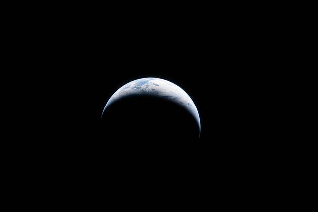 Earth is illuminated against the blackness of space in this...