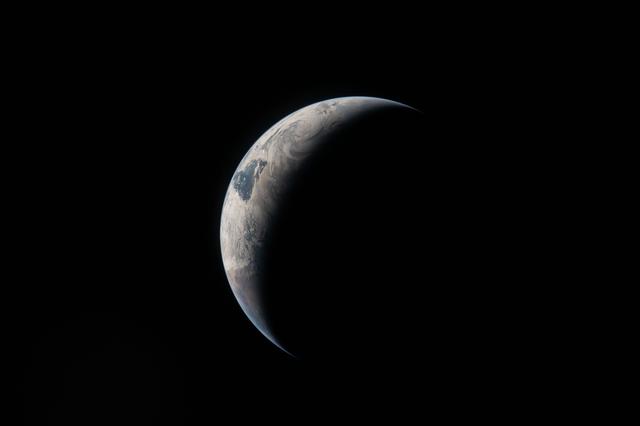 A thin arc glowing in the darkness of space. Sunlight traces...