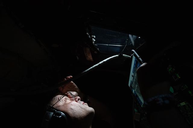 Artemis II Commander Reid Wiseman peers out the window of the...