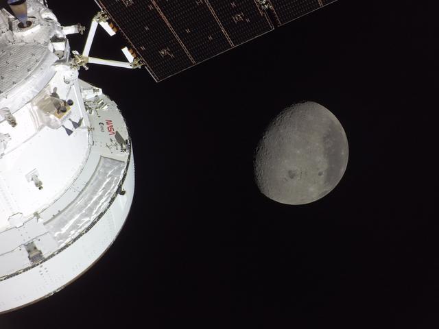 The Orion spacecraft is seen in the foreground lit up by the...