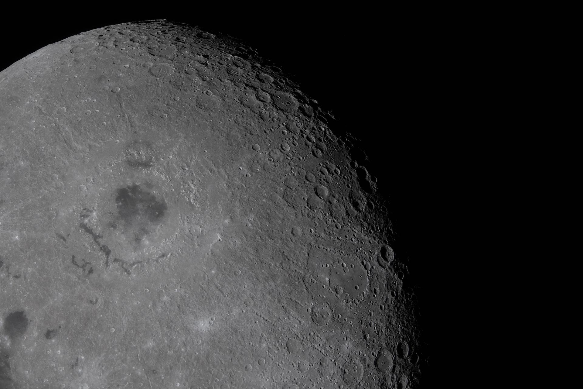 art002e009594 (April 6, 2026) – The Artemis II crew captured this view of the Moon’s Orientale basin during the lunar flyby. The basin stands out as a broad, circular feature surrounded by rugged terrain. Near the Moon’s limb, sunlight strikes the surface at a low angle, creating shadows that accentuate craters, ridges, and other topographic features. Secondary crater chains associated with Orientale extend across terrain to the northwest and south of the basin. Credit: NASA
