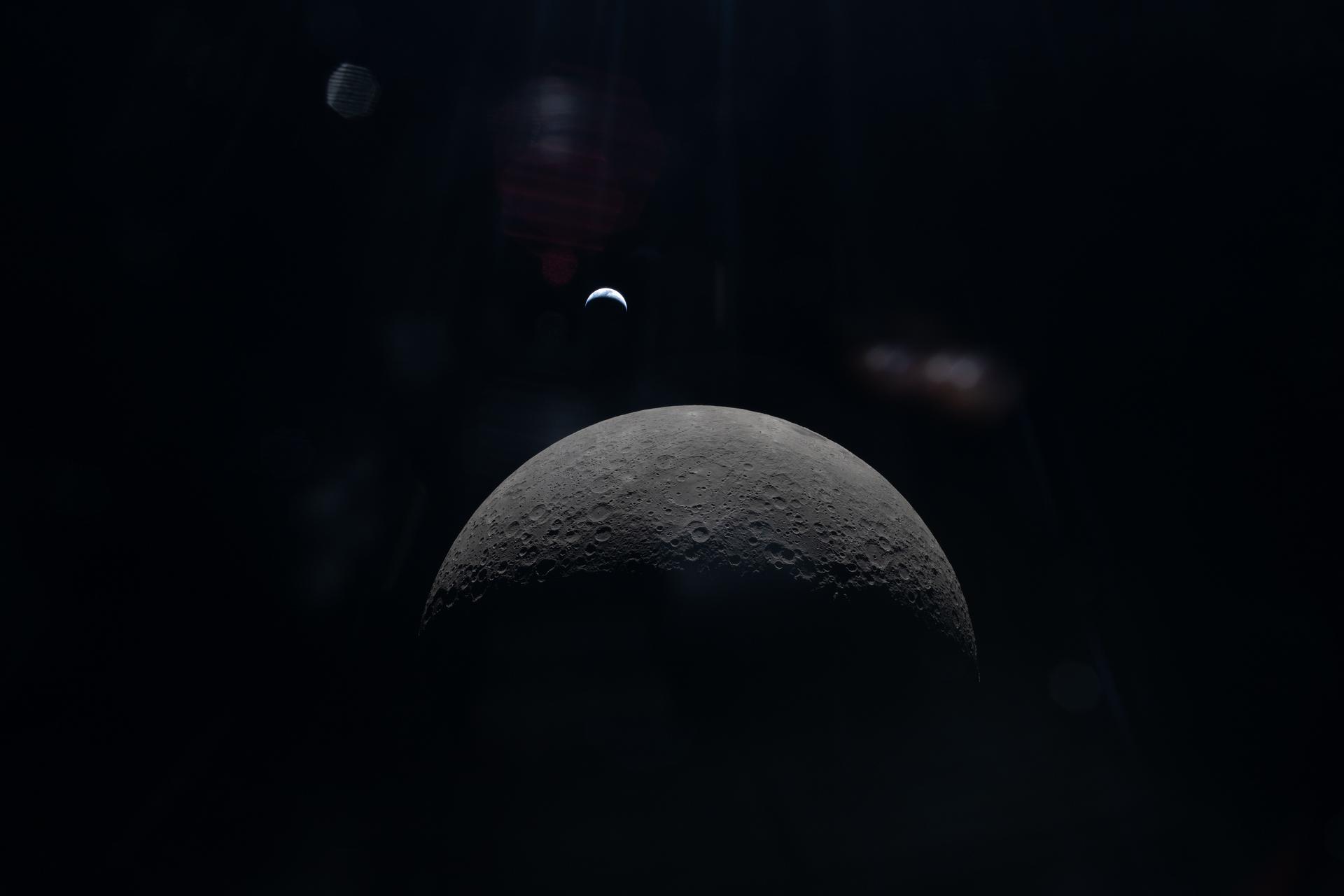 art002e015231 (April 6, 2026) – The Artemis II crew captures a faint view of a crescent Earth above the horizon...