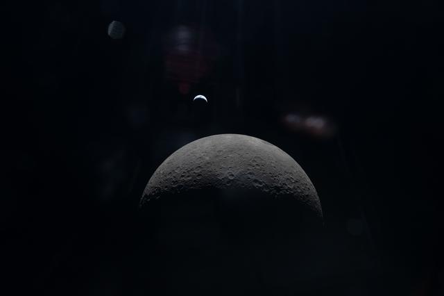 The Artemis II crew captures a faint view of a crescent Earth...