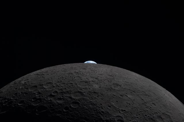 The Earth appears to be peeking out over the horizon of the...