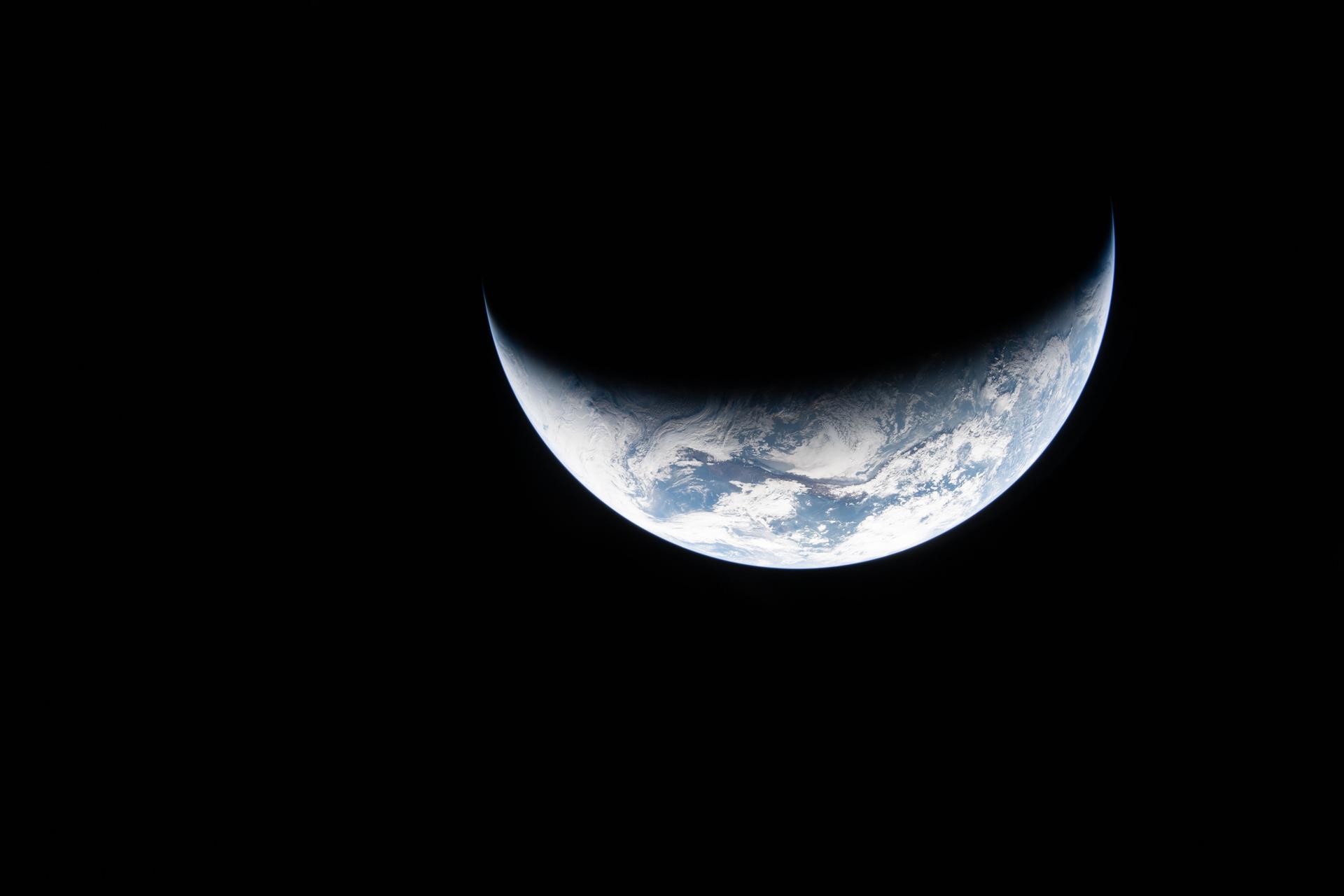 art002e023072 (April 2, 2026) - A sliver of Earth is illuminated against the blackness of space in this photo taken by an Artemis II crew member through an Orion spacecraft window on the second day of the mission. Credit: NASA