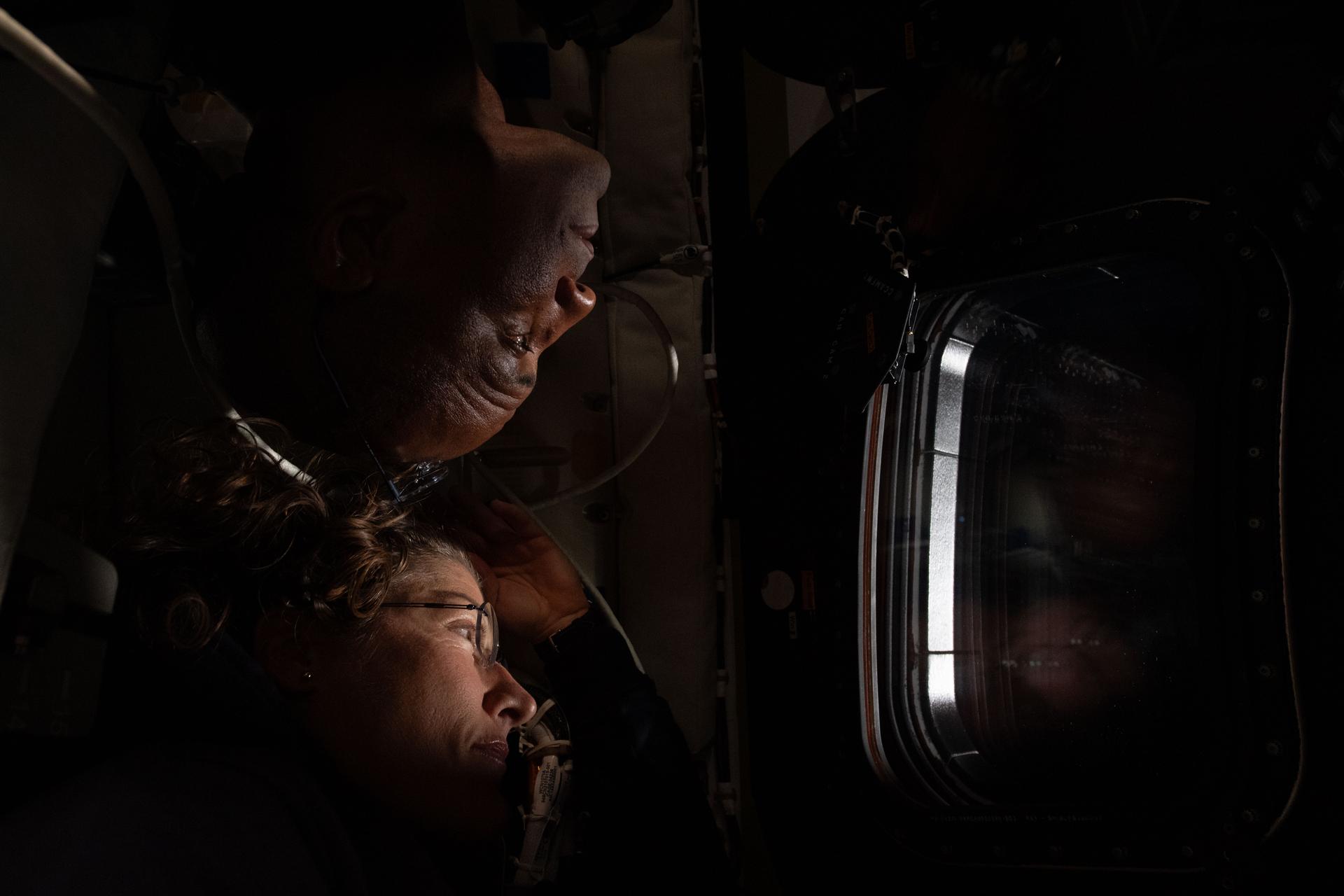 art002e025880 (April 6, 2026) - NASA astronauts Christina Koch (below) and Victor Glover (above) share a window inside the Orion spacecraft during the sixth day of the Artemis II mission. Flight Day 6 was the crew's lunar flyby day, during which they rotated roles taking photos, making annotations, and recording their observations of the lunar surface. Credit: NASA