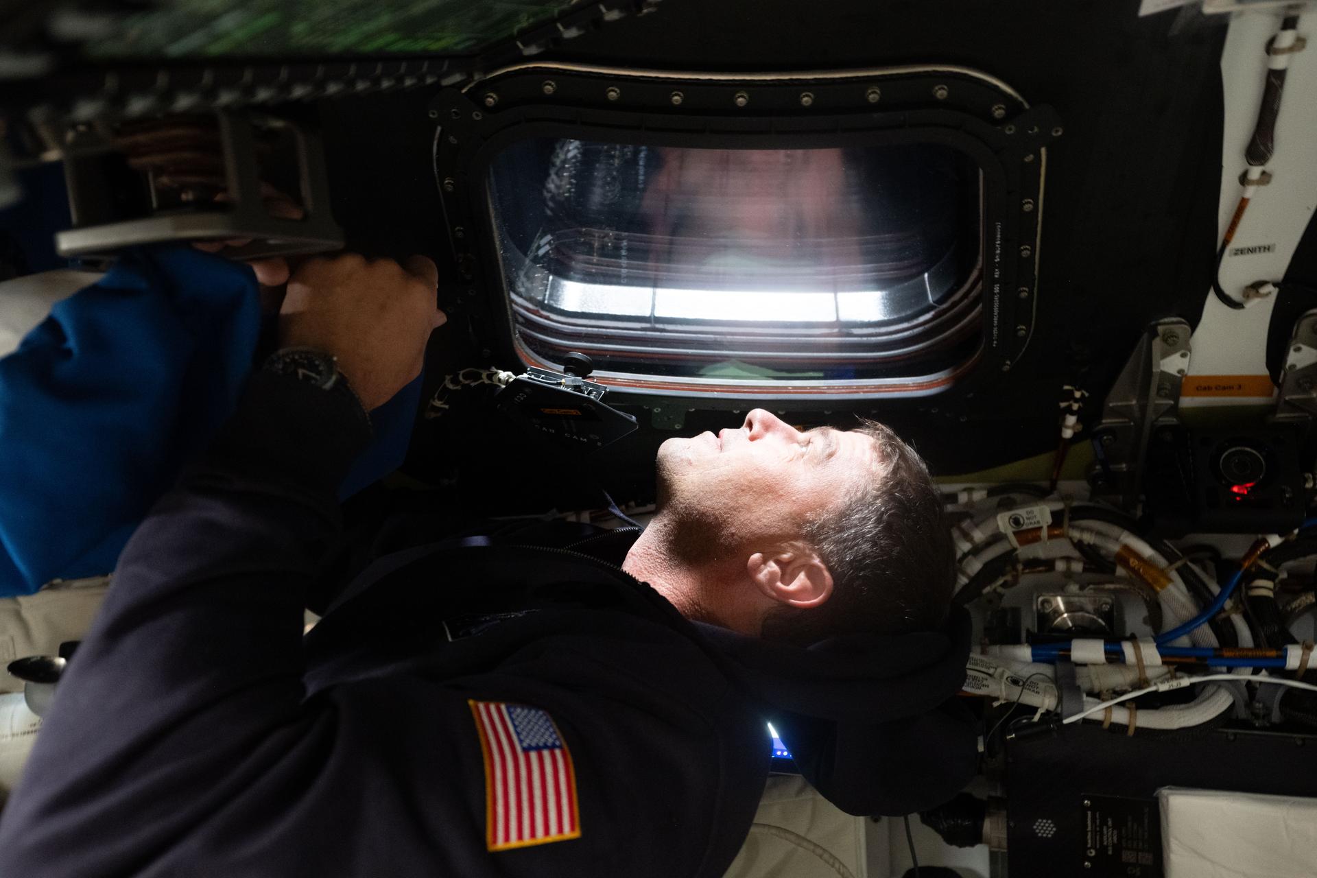 art002e029164 (April 6, 2026) - NASA astronaut and Artemis II commander Reid Wiseman gazes out the window of the Orion spacecraft upon the start of the sixth day of the mission and a few hours before the lunar flyby. Credit: NASA