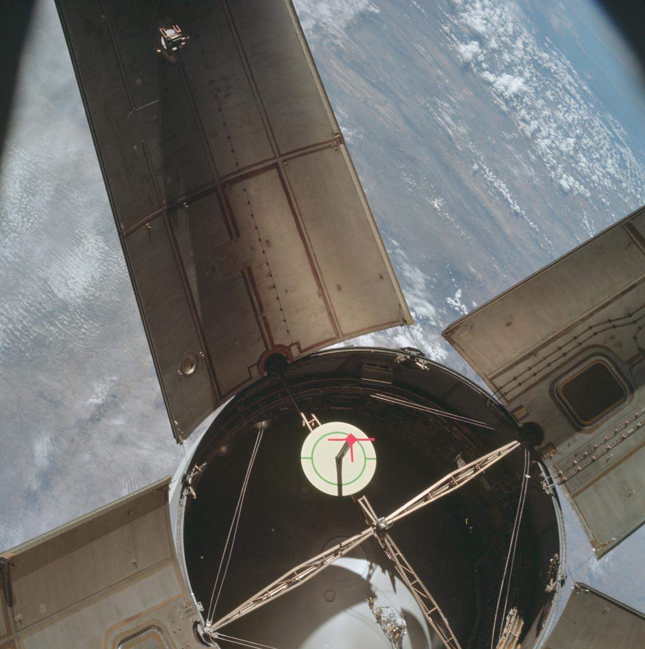 AS07-03-1535 (11 Oct. 1968) --- The expended Saturn IVB stage as photographed from the Apollo 7 spacecraft during transposition and docking maneuvers at an altitude of 126 nautical miles, at ground elapsed time of three hours, 11 minutes. The round, white disc inside the open panels of the Saturn IVB is a simulated docking target similar to that used on the lunar module for docking during lunar missions. The spacecraft is directly over Odessa-Midland, Texas. The view between the two panels (area of large puffy clouds) extends southwest across Texas into the Mexican State of Chihuahua. The distance between the Apollo 7 spacecraft and the S-IVB is approximately 50 feet.