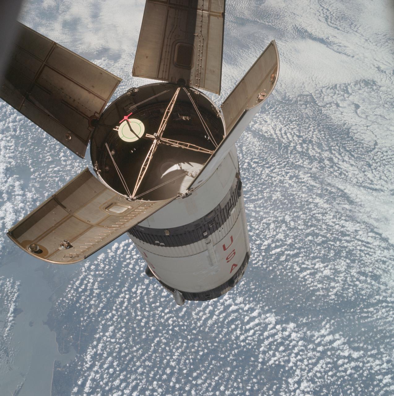 AS07-03-1541 (11 Oct. 1968) --- The expended Saturn IVB stage as photographed from the Apollo 7 spacecraft during transposition and docking maneuvers. St. Louis Bay and Lake Borgne area just east of New Orleans is seen below. The round, white disc inside the open panels of the Saturn IVB is a simulated docking target similar to that used on the lunar module for docking during lunar missions.
