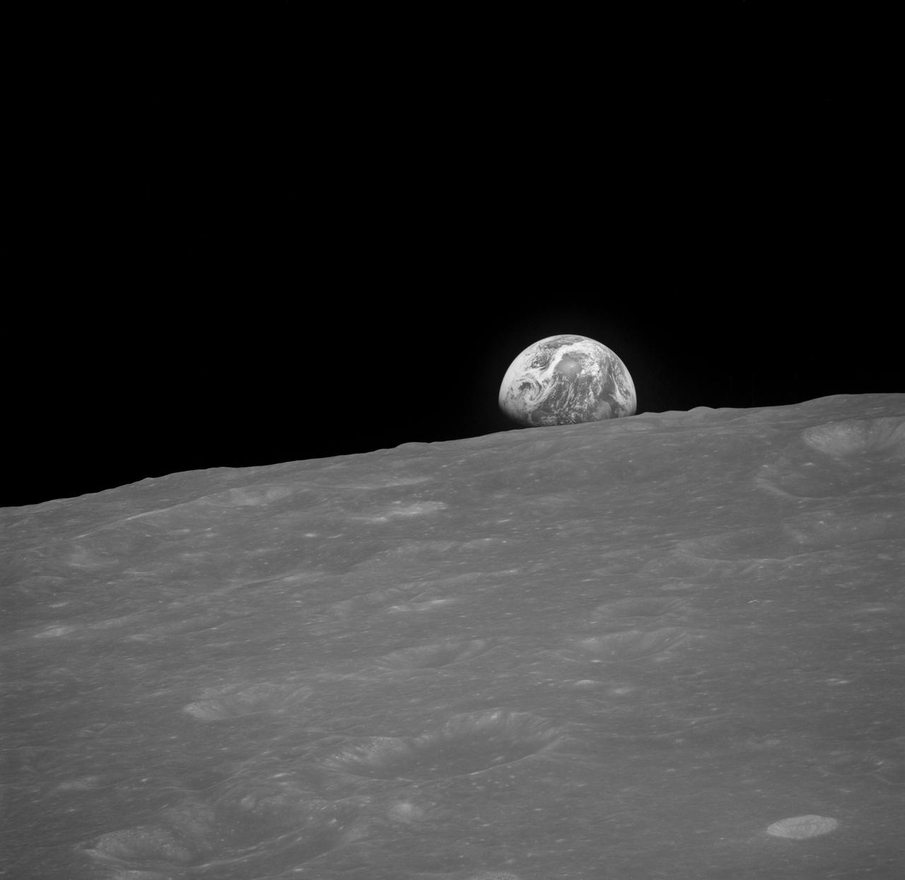 AS08-13-2329 (Dec. 1968) --- The Earth rising is about five degrees above the lunar horizon in this black and white telephoto view photographed from the Apollo 8 spacecraft near 110 degrees east longitude.  The horizon, about 570 kilometers (350 statute miles) from the spacecraft, is near the eastern limb of the Moon as viewed from Earth.  On Earth, 240,000 statute miles away, the sunset terminator crosses Africa.  The South Pole is in the white area near the left end of the terminator.  North and South America are under clouds.