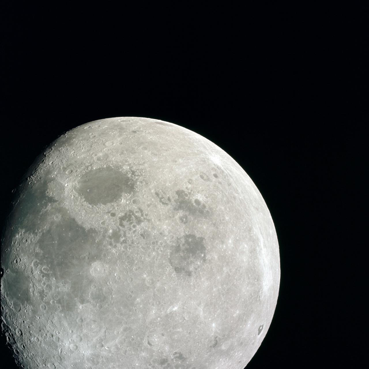 AS08-14-2505 (21-27 Dec. 1968) --- This photograph of a nearly full moon was taken from the Apollo 8 spacecraft at a point above 70 degrees east longitude. (Hold picture with moon's dark portion at left). Mare Crisium, the circular, dark-colored area near the center, is near the eastern edge of the moon as viewed from Earth. Mare Nectaris is the circular mare near the terminator. The large, irregular maira are Tranquillitatis and Fecunditatis. The terminator at left side of picture crosses Mare Tranquillitatis and highlands to the south. Lunar farside features occupy most of the right half of the picture. The large, dark-colored crater Tsiolkovsky is near the limb at the lower right. Conspicuous bright rays radiate from two large craters, one to the north of Tsiolkovsky, the other near the limb in the upper half of the picture. These rayed craters were not conspicuous in Lunar Orbiter photography due to the low sun elevations when the Lunar Orbiter photography was made. The crater Langrenus is near the center of the picture at the eastern edge of Mare Fecunditatis. The lunar surface probably has less pronounced color that indicated by this print.