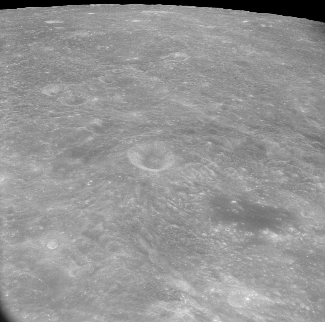 AS8-17-2744 (21-27 Dec. 1968) --- Oblique view of the lunar surface taken from the Apollo 8 spacecraft looking westward showing typical lunar farside terrain. (HOLD PICTURE SO THAT DARK IRREGULAR AREA SURROUNDED BY LIGHT SPOTS IS IN THE LOWER RIGHT QUARTER). The sharp crater near the center of then scene is near 117 degrees east longitude and 5 degrees south latitude; and it is 25 kilometers (15 statute miles) in diameter. That crater is on the rim of a large crater that occupies the lower right quarter of the photograph.