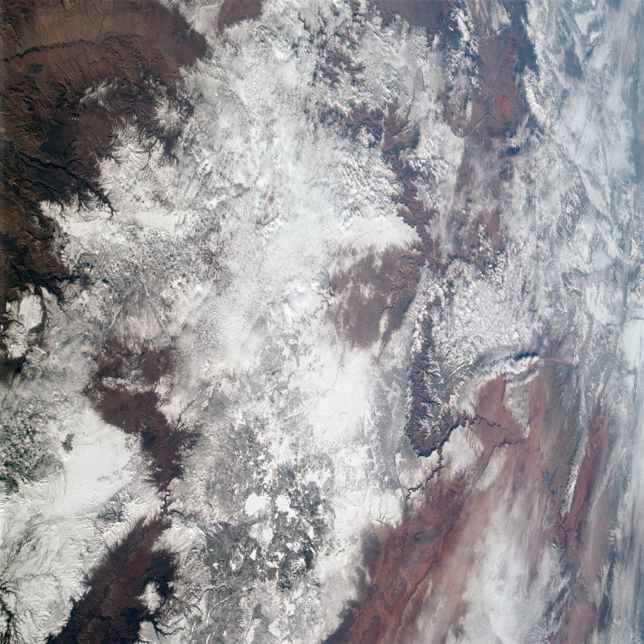 AS09-20-3137 (3-13 March 1969) --- The Grand Canyon is sharply etched on the snow-covered Colorado Plateau in Arizona in this photograph from the Apollo 9 spacecraft during its Earth-orbital mission. Lake Powell behind Glen Canyon Dam is in the upper right corner. Humphreys Peak and the many volcanic craters around the San Francisco Mountains near Flagstaff, Arizona, are right of center. Prescott is under clouds at lower center.