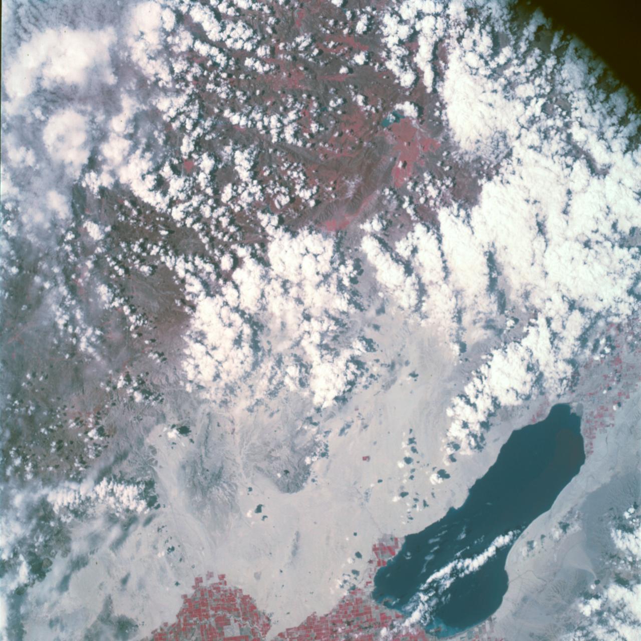 Earth Observation taken by the Apollo 9 crew. View is of Salton Sea and Imperial Valley in California. Latitude was 33.09 N by Longitude 116.14 W, Overlap was 50%, Altitude miles were 103 and cloud cover was 35%. This imagery taken as part of the NASA S0-65 Experiment "Multispectral Terrain Photography". The experiment provides simultaneous satellite photography of the Earth's surface in three distinct spectral bands. The photography consists of four almost spatially identical photographs. The images of ground objects appear in the same coordinate positions on all four photos in the multispectral set within the opto-mechanical tolerances of the Hasselblad cameras in the Apollo 9 spacecraft. Band designation for this frame is A.  Film and filter is Ektachrome SO-368,Infrared Color Wratten 15.  Mean Wavelength of Sensitivity is green,red and infrared. The Nominal Bandpass is total sensitivity of all dye layers 510-900nm.