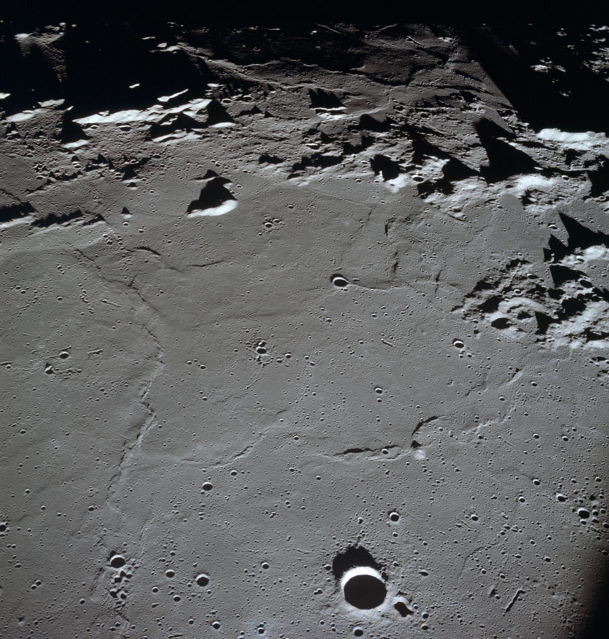 AS10-27-3907 (18-26 May 1969) --- Apollo 10 westward view across Apollo Landing Site 3 in the Central Bay. Apollo Landing Site 3 is in the middle distance at the left margin of the pronounced ridge in the left half of the photograph. Bruce, the prominent crater, near the bottom of the scene, is about 6 kilometers (3.7 statute miles) in diameter. Topographic features on the surface of the Central Bay are accentuated by the low sun angle. Sun angles range from near 6 degrees at the bottom of the photograph to less than one degree at the top.