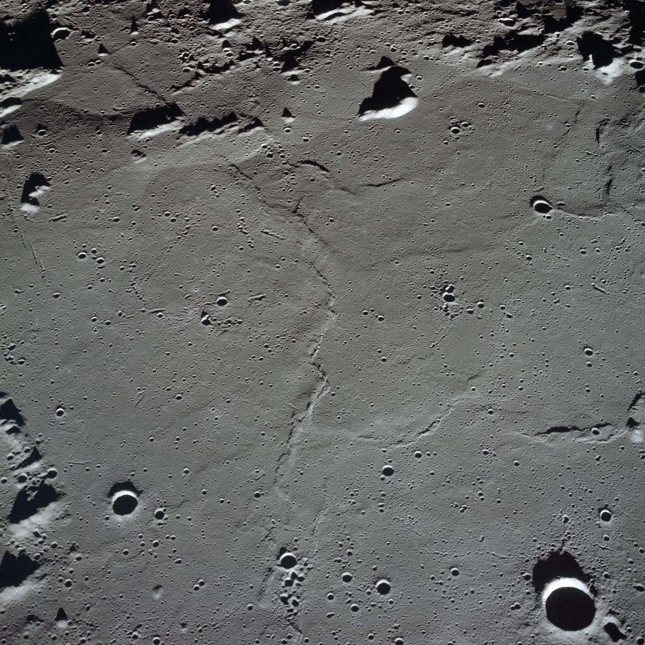 AS10-27-3908 (18-26 May 1969) --- An Apollo 10 photograph of the lunar nearside looking westward across Apollo Landing Site 3 in Central Bay. Bruce, the prominent crater in the lower right corner, is about 3.7 statute miles in diameter. Topographic features on the surface of Central Bay are accentuated by the low sun angle.