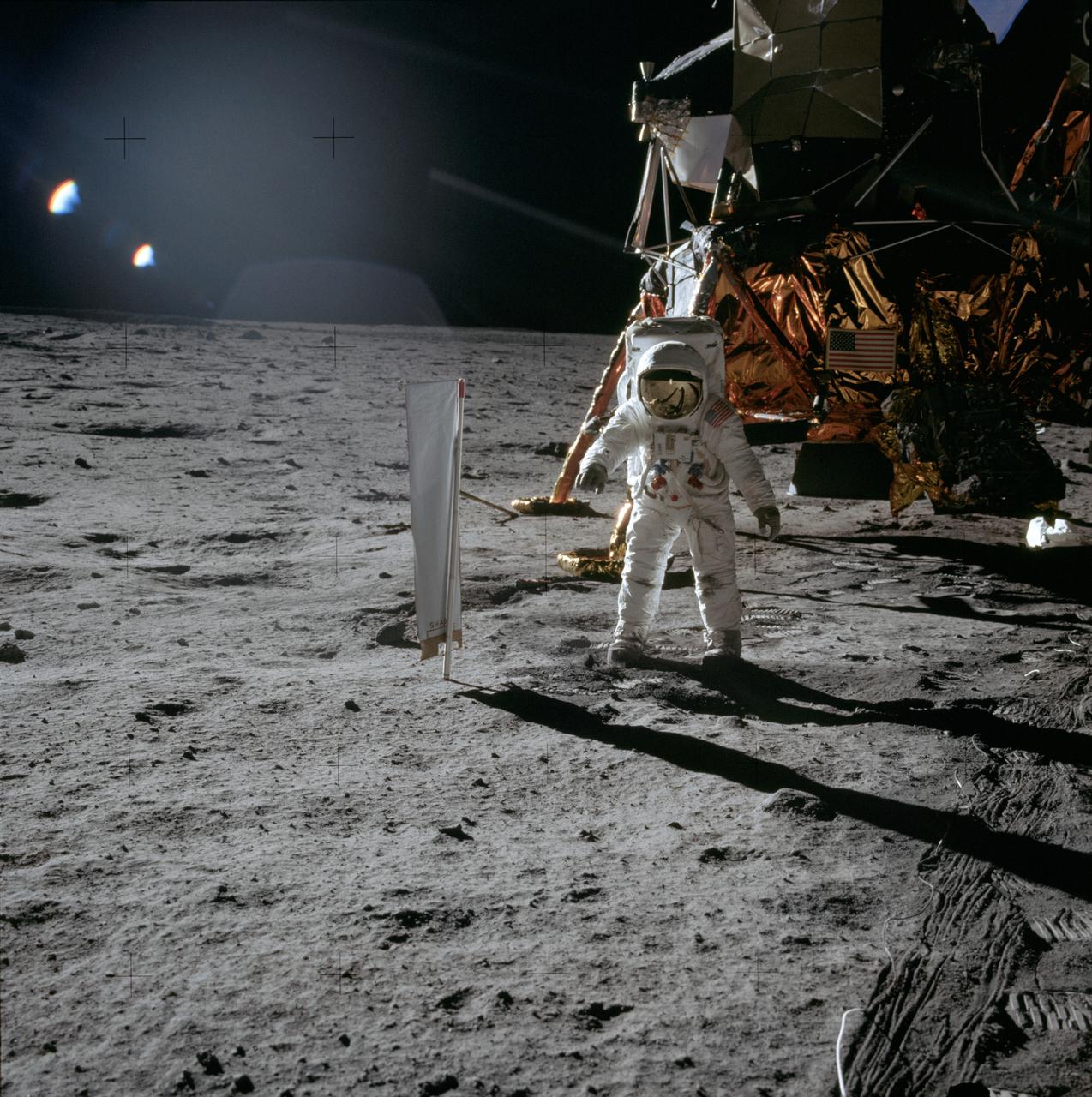 AS11-40-5873 (20 July 1969) --- Astronaut Edwin E. Aldrin Jr., lunar module pilot, is photographed during the Apollo 11 extravehicular activity (EVA) on the lunar surface. In the right background is the lunar module. On Aldrin's right is the Solar Wind Composition (SWC) experiment, already deployed. This photograph was taken by astronaut Neil A. Armstrong, commander, with a 70mm lunar surface camera.