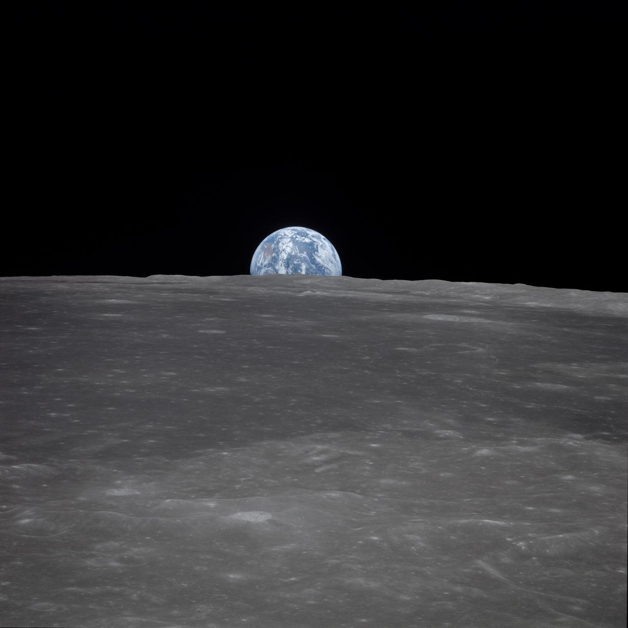 AS11-44-6548 (16-24 July 1969) --- This view from the Apollo 11 spacecraft shows Earth rising above the moon's horizon. The lunar terrain pictured is in the area of Smyth's Sea on the nearside. Coordinates of the center of the terrain are 86 degrees east longitude and 3 degrees north latitude. While astronauts Neil A. Armstrong, commander, and Edwin E. Aldrin Jr., lunar module pilot, descended in the Lunar Module (LM) "Eagle" to explore the Sea of Tranquility region of the moon, astronaut Michael Collins, command module pilot, remained with the Command and Service Modules (CSM) "Columbia" in lunar orbit.