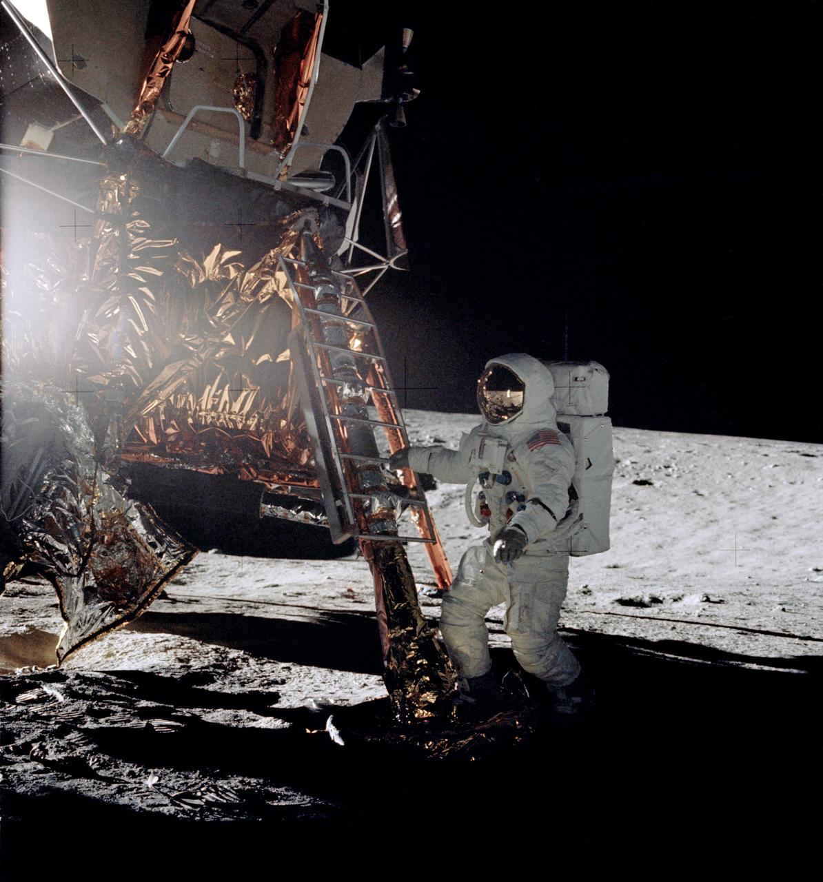 AS12-46-6729 (19 Nov. 1969) --- Astronaut Alan L. Bean, lunar module pilot for the Apollo 12 lunar landing mission, steps from the ladder of the Lunar Module to join astronaut Charles Conrad Jr., commander, in extravehicular activity on Nov. 19, 1969. Astronaut Richard F. Gordon Jr., command module pilot, remained with the Command and Service Modules in lunar orbit.