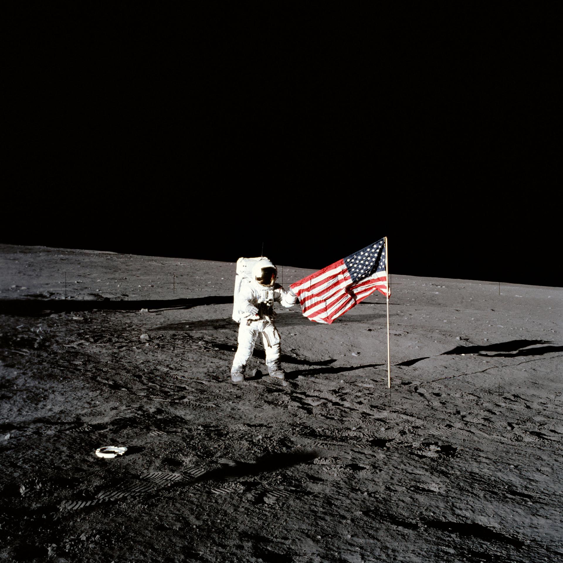 Charles Conrad stands beside the US flag on the surface of the Moon during Apollo 12