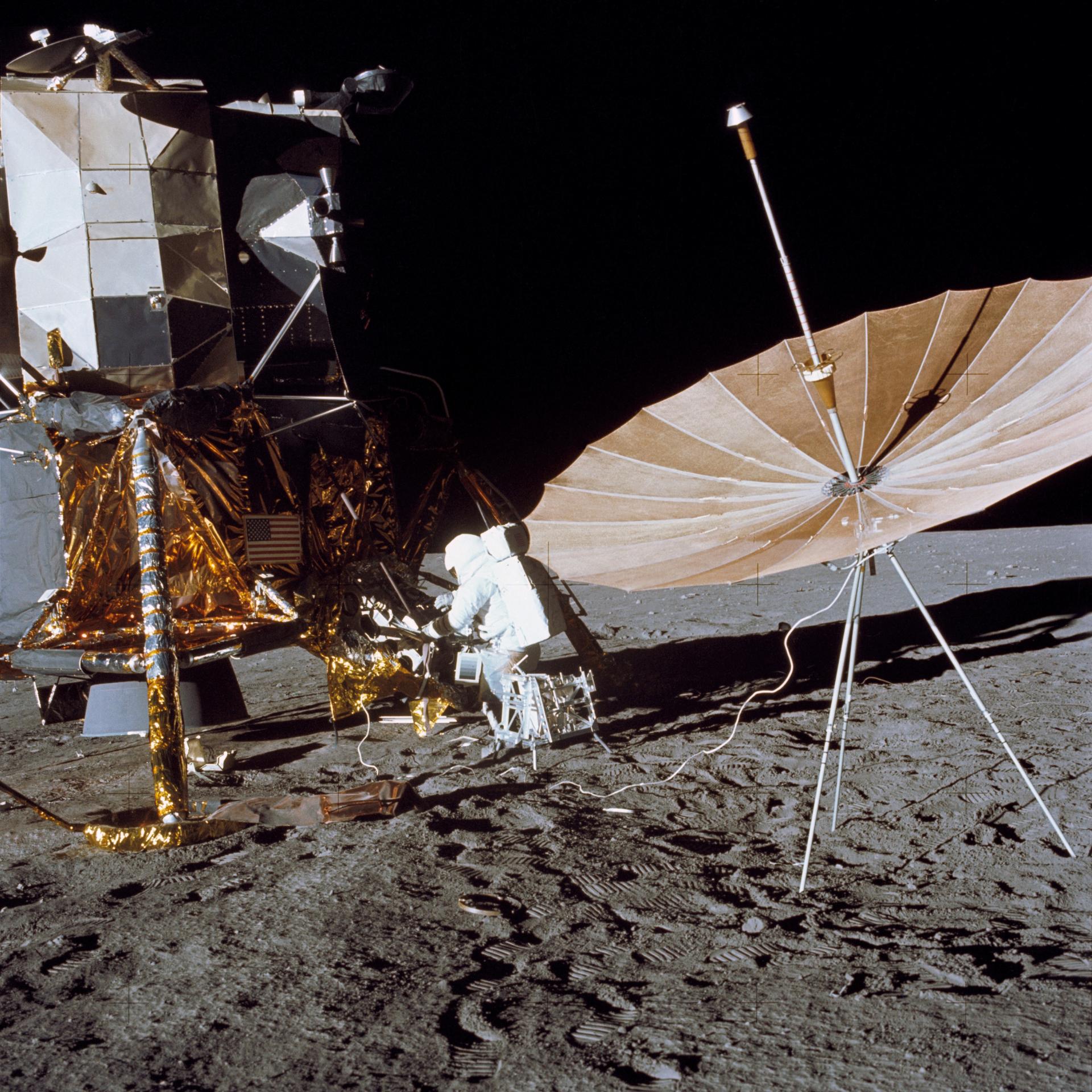 Astronaut Charls Conrad stands at the Module Equipment Stowage Assembly (MESA) on the Lunar Module (LM) following the first Apollo 12 extravehicular activity (EVA) on the lunar surface. The erectable S-band antenna is already deployed at right.