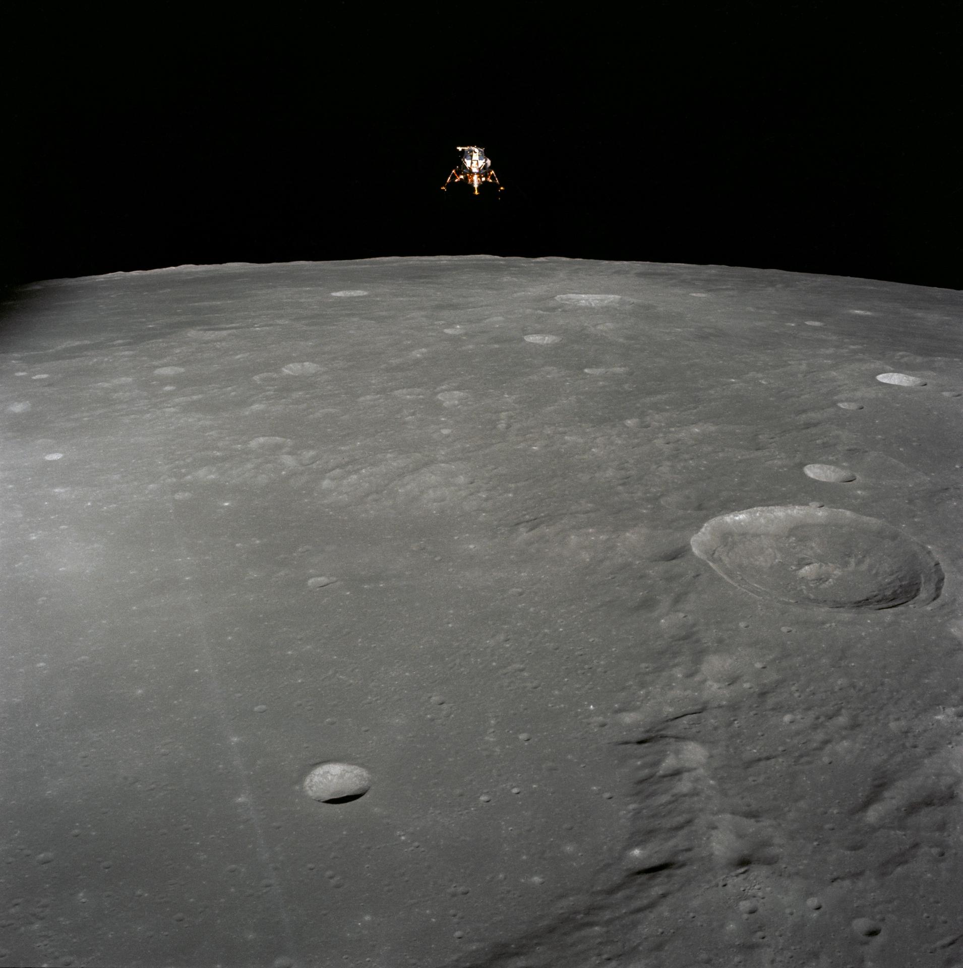 View of the Apollo 12 lunar module in the distance as both it and the command module orbit the Moon.