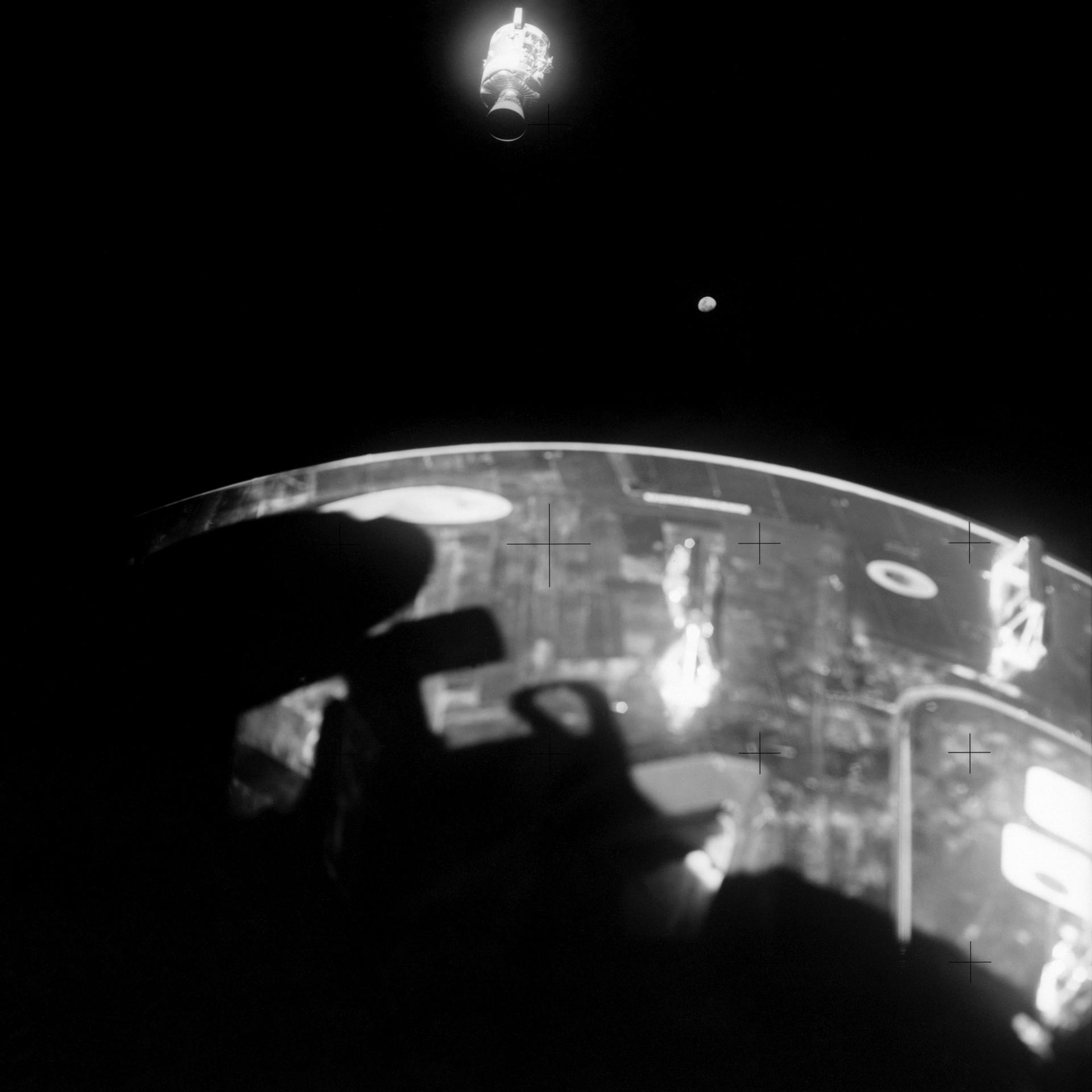 View of the damaged Apollo 13 service module in the distance, with the command module in the foreground.