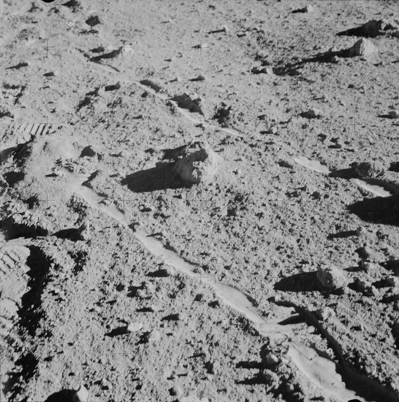 AS14-64-9129 (6 Feb. 1971) --- The two moon-exploring crew men of the Apollo 14 lunar landing mission, photographed and collected the large rock pictured just above the exact center of this picture. (Hold picture with the NASA photographic number at lower right hand corner.) The rock, casting a shadow off to the left, is lunar sample number 14321, referred to as a basketball-sized rock by newsmen and nicknamed "Big Bertha" by principal investigators. It lies between the wheel tracks made by the modular equipment transporter (MET) or rickshaw-type portable workbench. A few prints of the lunar overshoes of the crew members are at the left. This photo was made near the boulder field near the rim of Cone Crater.