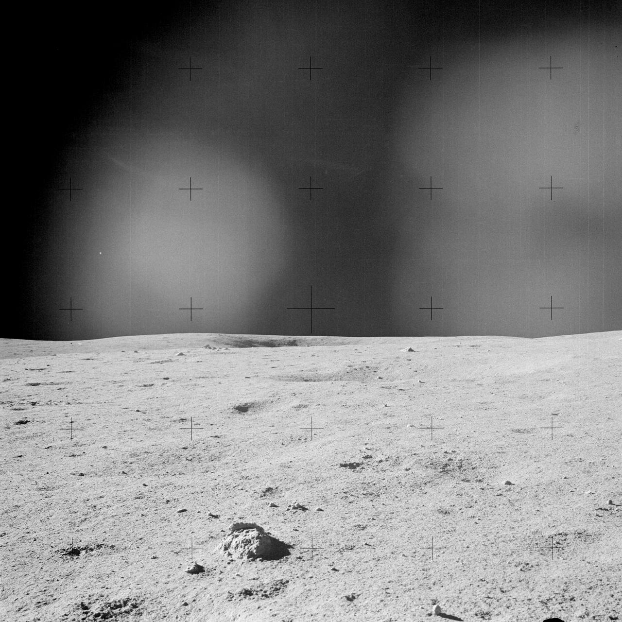 AS14-64-9181 (5-6 Feb. 1971) --- A view of the lunar terrain at the Apollo 14 Fra Mauro landing site as photographed through the left window of the Lunar Module (LM). Note the clump of lunar soil in the foreground, and a crater in the center on the horizon. While astronauts Alan B. Shepard Jr., commander; and Edgar D. Mitchell, lunar module pilot; descended in the LM to explore the moon, astronaut Stuart A. Roosa, command module pilot, remained with the Command and Service Modules (CSM) in lunar orbit.