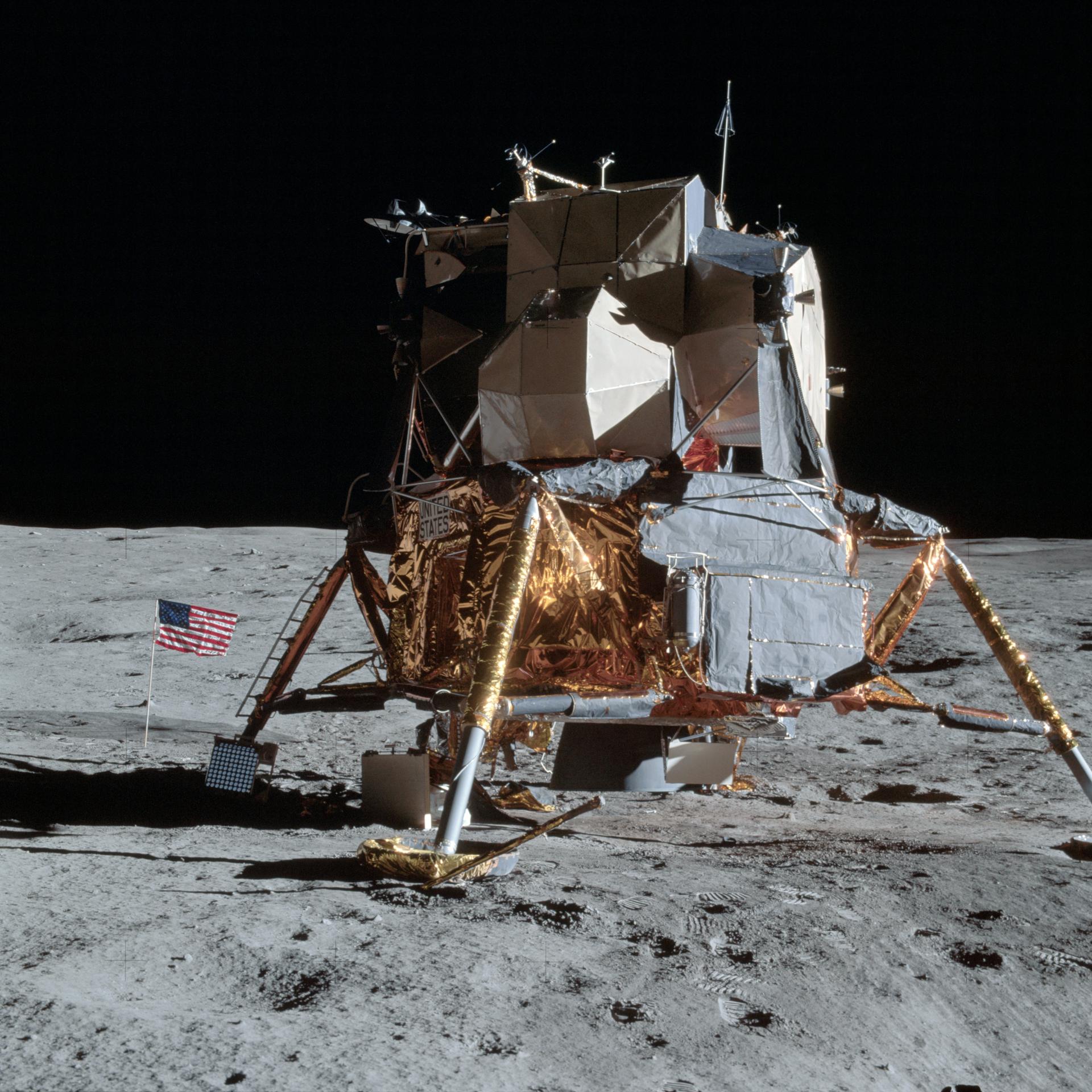 The Apollo 14 lunar module is seen on the Moon with the American flag positioned next to it.