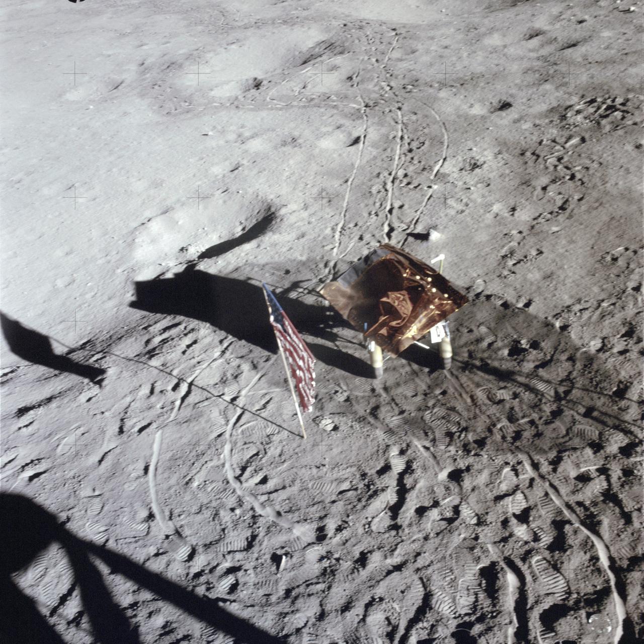 AS14-66-9325 (5 Feb. 1971) --- The third United States flag to be deployed on the lunar surface, footprints, wheel tracks and the "Rickshaw"-type portable workbench, as seen by the two moon-exploring astronauts from inside the Lunar Module (LM), give evidence of a busy first extravehicular activity (EVA) period. The two-wheeled cart is the Apollo modularized equipment transporter (MET), covered with a sheet of foil material to protect the cameras and rock box between EVAs. While astronauts Alan B. Shepard Jr., commander, and Edgar D. Mitchell, lunar module pilot, descended in the LM, astronaut Stuart A. Roosa, command module pilot, remained with the Command and Service Modules (CSM) in lunar orbit.