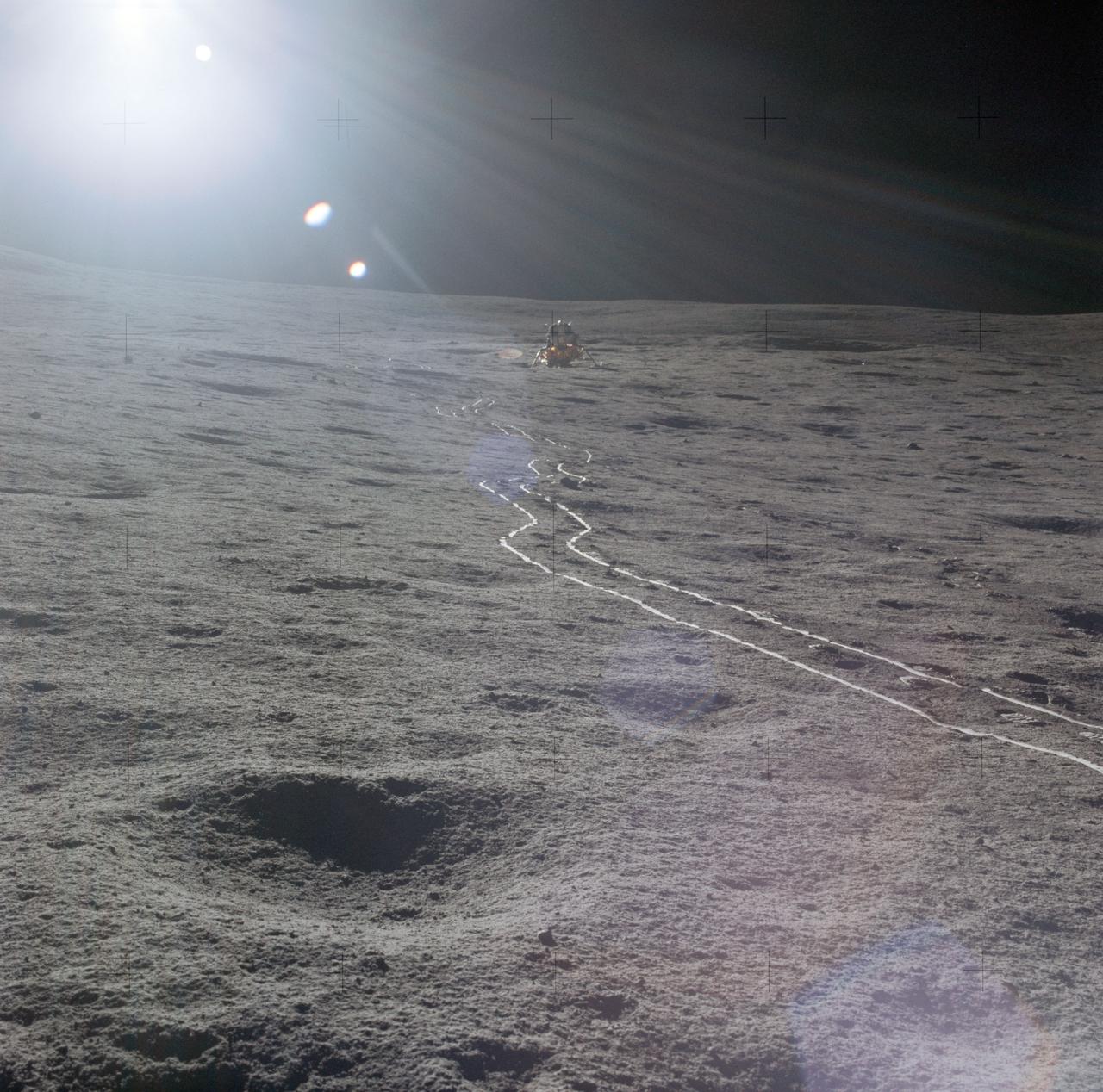 AS14-67-9367 (5 Feb. 1971) --- The Apollo 14 Lunar Module (LM) as seen by the two moon-exploring crewmen of the Apollo 14 lunar landing mission, photographed against a brilliant sun glare during the first extravehicular activity (EVA). A bright trail left in the lunar soil by the two-wheeled modularized equipment transporter (MET) leads from the LM. While astronauts Alan B. Shepard Jr., commander, and Edgar D. Mitchell, lunar module pilot, were exploring the moon, astronaut Stuart A. Roosa, command module pilot, was maneuvering the Command and Service Modules (CSM) in lunar orbit.