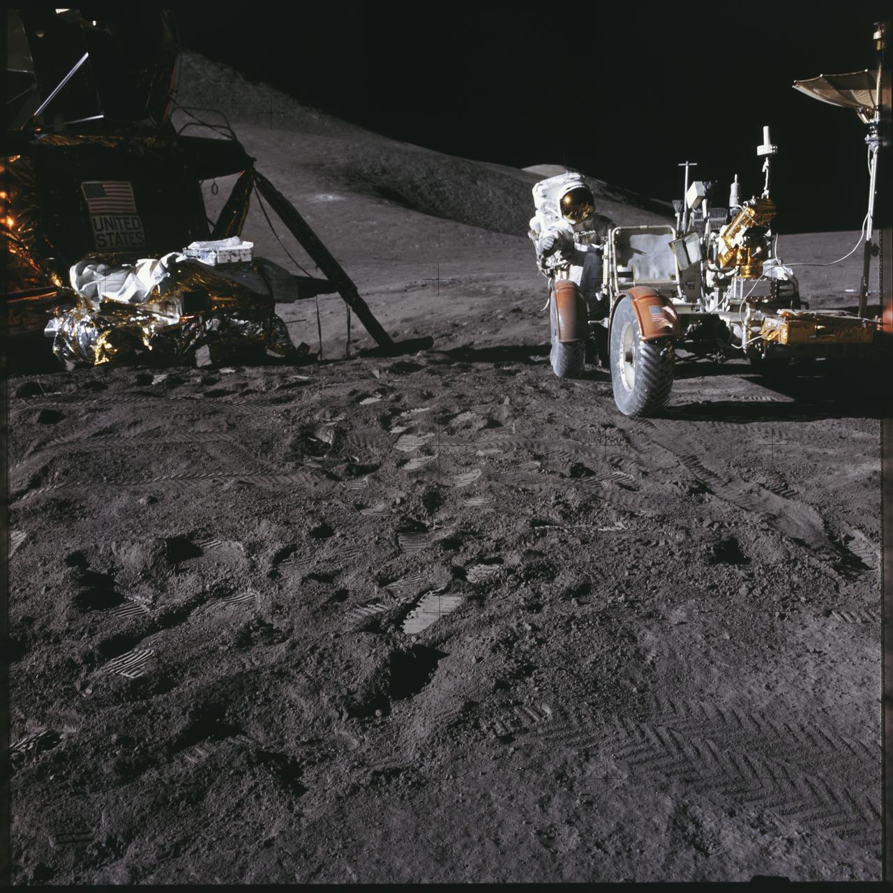 AS15-86-11601 (31 July 1971) --- Astronaut James B. Irwin, lunar module pilot, works at the Lunar Roving Vehicle (LRV) during the first Apollo 15 lunar surface extravehicular activity (EVA) at the Hadley-Apennine landing site. The Lunar Module (LM) "Falcon" is on the left. The undeployed Laser Ranging Retro Reflector (LR-3) lies atop the LM's modular equipment stowage assembly (MESA). This view is looking slightly west of south. Hadley Delta and the Apennine Front are in the background to the left. St. George crater is approximately five kilometers (about three statute miles) in the distance behind Irwin's head. This photograph was taken by astronaut David R. Scott, commander. While astronauts Scott and Irwin descended in the LM to explore the moon, astronaut Alfred M. Worden, command module pilot, remained with the Command and Service Modules (CSM) in lunar orbit.