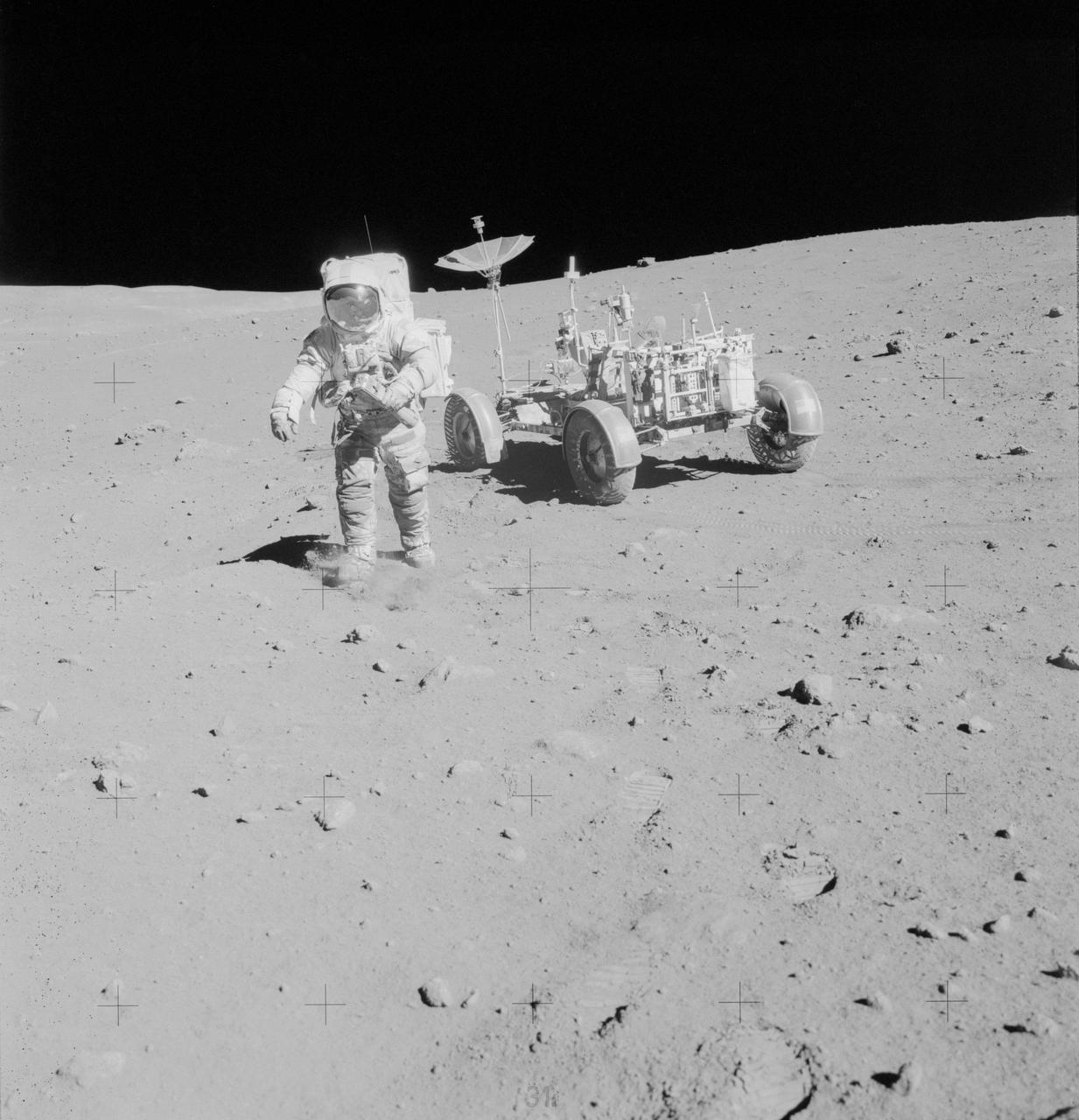 AS15-82-11168 (2 Aug. 1971) --- Astronaut James B. Irwin, lunar module pilot, walks away from the Lunar Roving Vehicle (LRV) during the third Apollo 15 lunar surface extravehicular activity (EVA) at the Hadley-Apennine landing site. The LRV is parked a short distance from the rim of Hadley Rille. The far wall of the rille is in the distance at extreme upper left. Irwin is holding the 500mm Hasselblad camera in his left hand. This photograph was taken by astronaut David R. Scott, commander. While astronauts Scott and Irwin descended in the Lunar Module (LM) to explore the moon, astronaut Alfred M. Worden, command module pilot, remained with the Command and Service Modules (CSM) in lunar orbit.