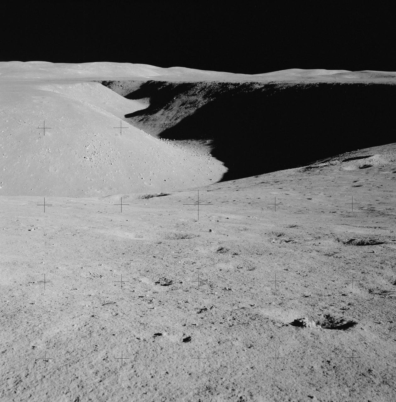 AS15-85-11425 (31 July 1971) --- A view of Hadley Rille, looking northwest, as photographed from near Station No. 2 (St. George Crater) during the first Apollo 15 lunar surface extravehicular activity (EVA). This picture shows layering in the rille wall and blocks on the floor of the rille. The feature referred to as the "Terrace" is visible on the right (east) side of the rille. While astronauts David R. Scott, commander, and James B. Irwin, lunar module pilot, descended in the Lunar Module (LM) "Falcon" to explore the moon, astronaut Alfred M. Worden, command module pilot, remained with the Command and Service Module's (CSM) in lunar orbit.