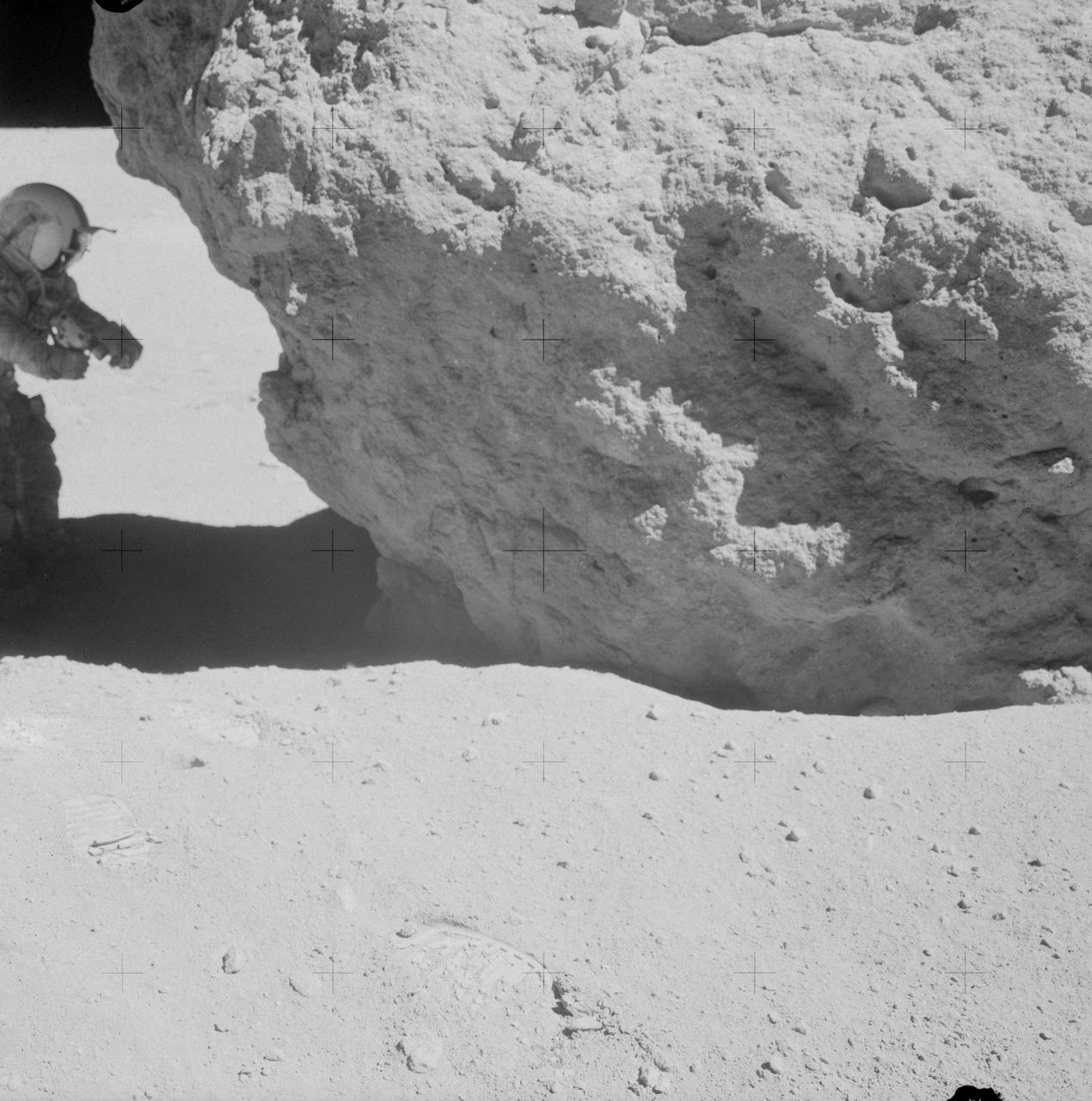 AS16-106-17413 (23 April 1972) --- Astronaut John W. Young, commander of the Apollo 16 lunar landing mission, looks over a large boulder at Station No.13 during the third Apollo 16 extravehicular activity (EVA) at the Descartes landing site. This was the site of the permanently shadowed soil sample which was taken from a hole extending under overhanging rock. Astronaut Charles M. Duke Jr., lunar module pilot, took this photograph. Concerning Young's reaching under the big rock, Duke remarked: "You do that in west Texas and you get a rattlesnake!"