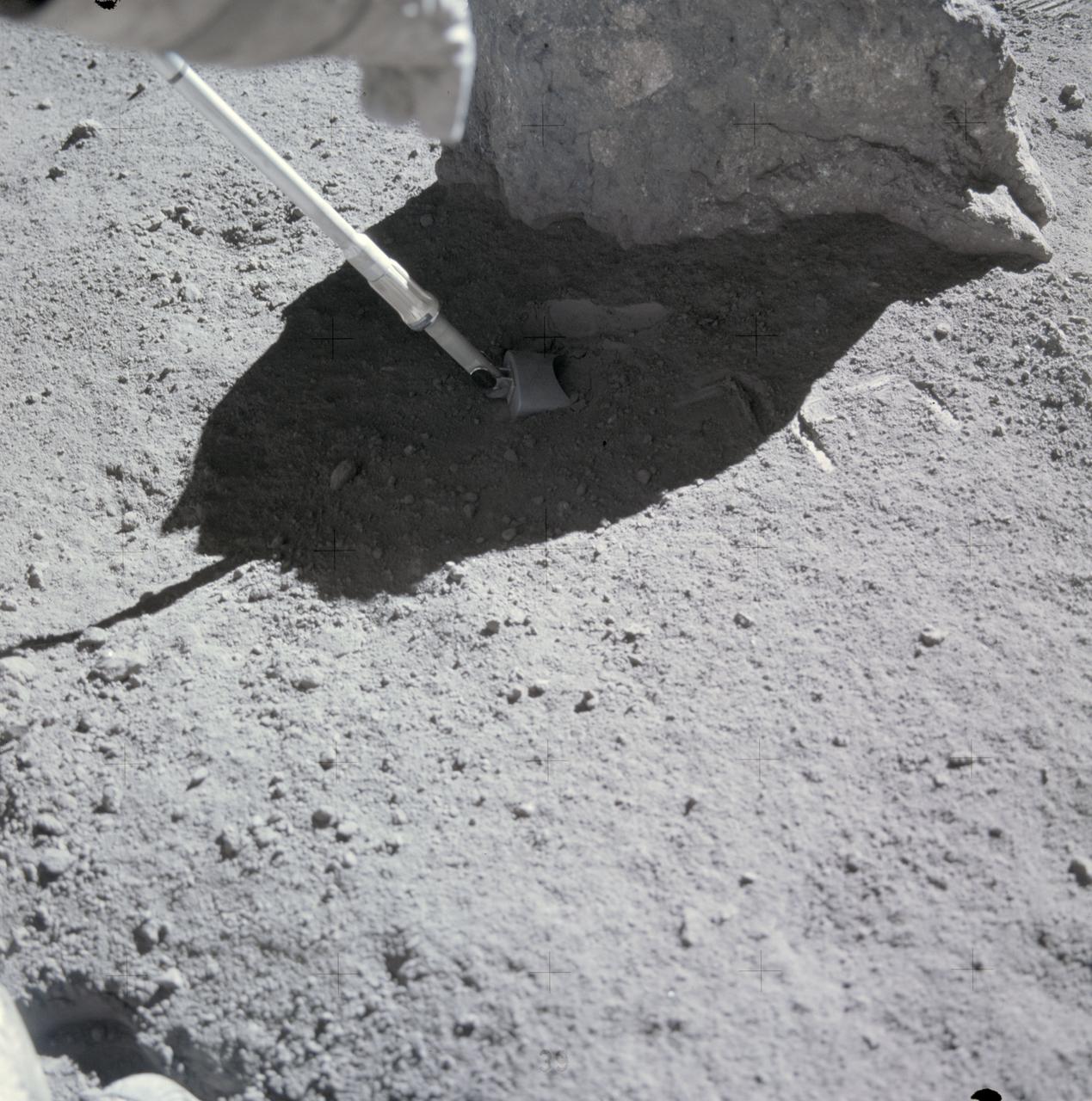 AS16-107-17561 (16-27 April 1972) --- One of the Apollo 16 astronauts scoops up lunar soil at the base of a small boulder at Station No. 9 during the second Apollo 16 extravehicular activity (EVA) at the Descartes landing site. Depressions to the right of the scoop were made when a surface sample was taken. This photograph was taken just before the boulder was rolled over. While astronauts John W. Young, commander; and Charles M. Duke Jr., lunar module pilot; descended in the Apollo 16 Lunar Module (LM) "Orion" to explore the Descartes highlands landing site on the moon, astronaut Thomas K. Mattingly II, command module pilot, remained with the Command and Service Modules (CSM) "Casper" in lunar orbit.