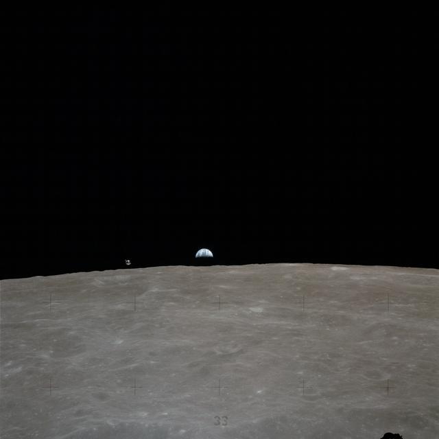 NASA image: Apollo 16 Mission image - Earth rises over the lunar horizon, with the Apollo 16 Command and Services Modules (CSM) to the left of the Earth.