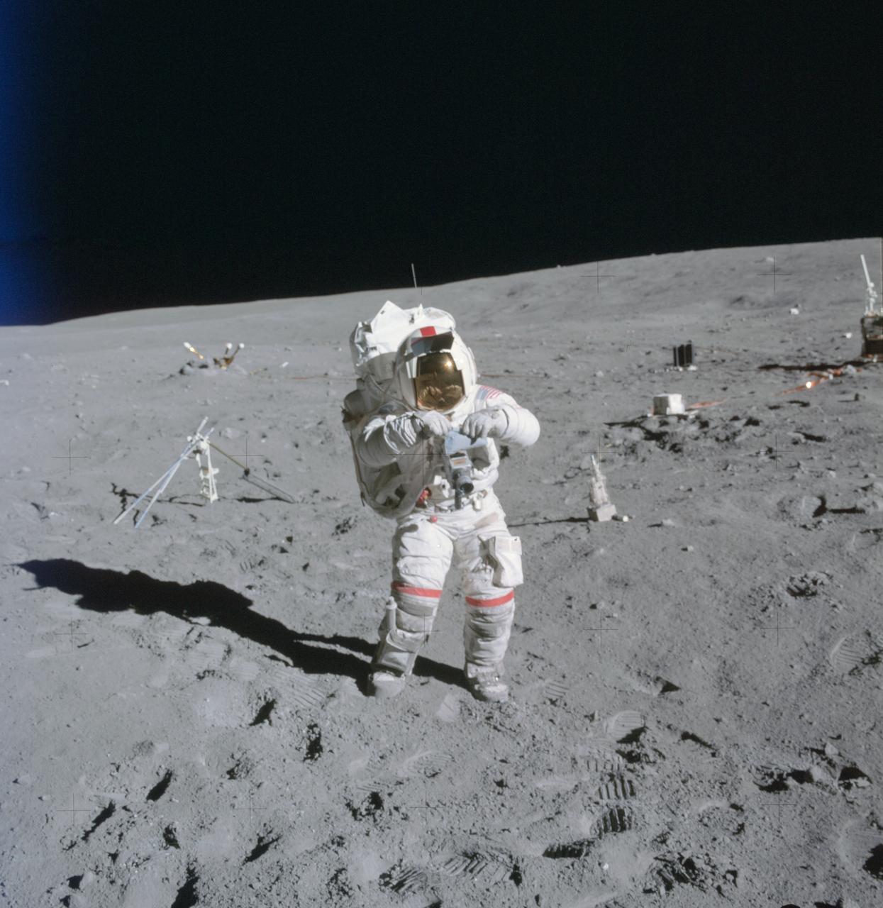AS16-114-18388 (21 April 1972) --- Astronaut John W. Young, commander of the Apollo 16 lunar landing mission, stands at the Apollo Lunar Surface Experiments Package (ALSEP) deployment site during the first Apollo 16 extravehicular activity (EVA) at the Descartes landing site. The components of the ALSEP are in the background. The lunar surface drill is just behind and to the right of astronaut Young. The drill's rack and bore stems are to the left. The three-sensor Lunar Surface Magnetometer is beyond the rack. The dark object in the right background is the Radioisotope Thermoelectric Generator (RTG). Between the RTG and the drill is the Heat Flow Experiment. A part of the Central Station is at the right center edge of the picture. This photograph was taken by astronaut Charles M. Duke Jr., lunar module pilot.