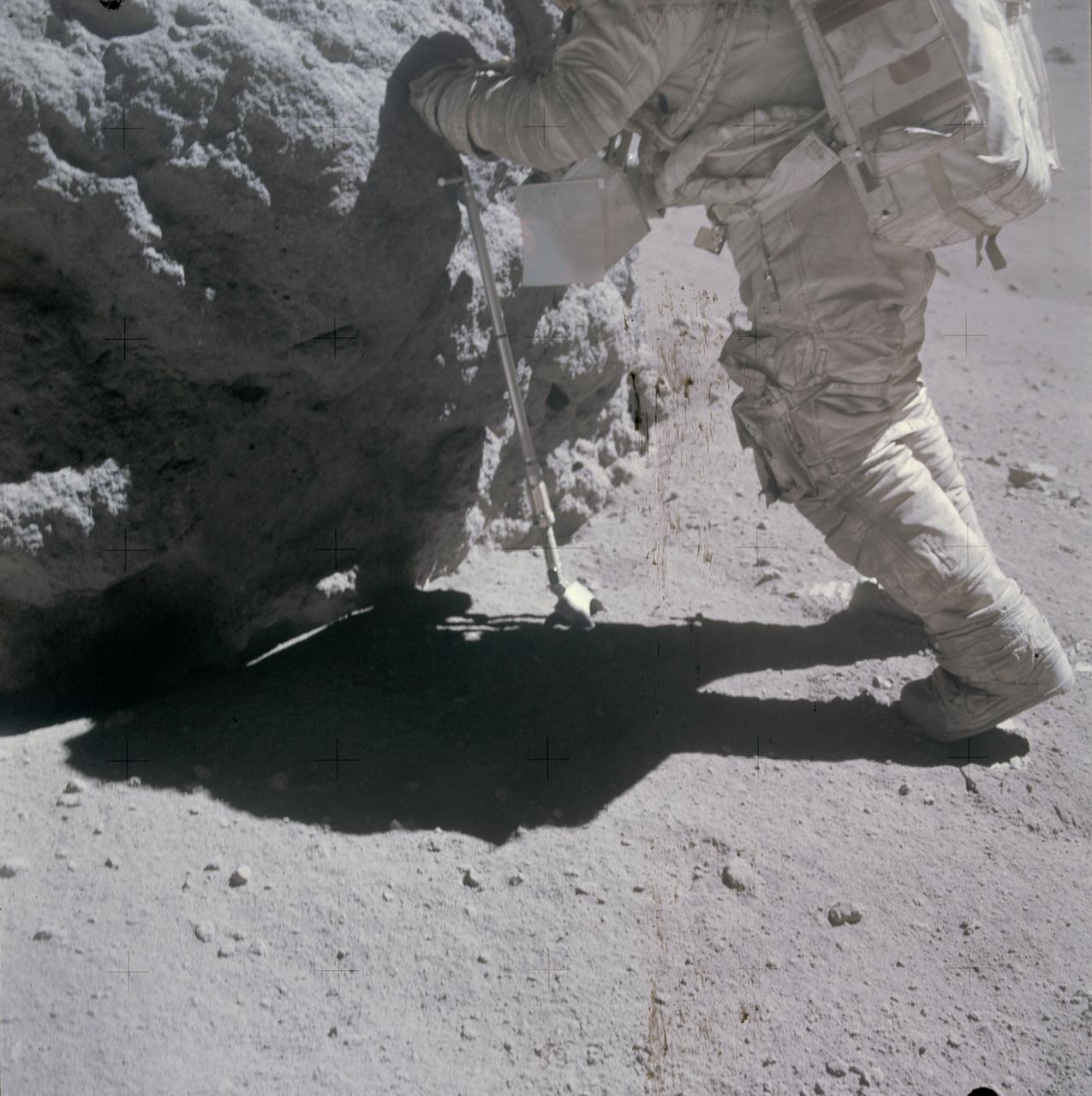 AS16-116-18671 (23 April 1972) --- Astronaut Charles M. Duke Jr., lunar module pilot, works at the "Shadow Rock", discovered during the missions third extravehicular activity (EVA) in the area of North Ray Crater (Station 13), April 23, 1972. The scoop, a geological hand tool, leans against the rock. This view was exposed by astronaut John W. Young, commander. The two moon-exploring crew men sampled this rock, which got its name because of a permanently shadowed area it protected. While astronauts Young and Duke descended in the Apollo 16 Lunar Module (LM) "Orion" to explore the Descartes highlands landing site on the moon, astronaut Thomas K. Mattingly II, command module pilot, remained with the Command and Service Modules (CSM) "Casper" in lunar orbit.