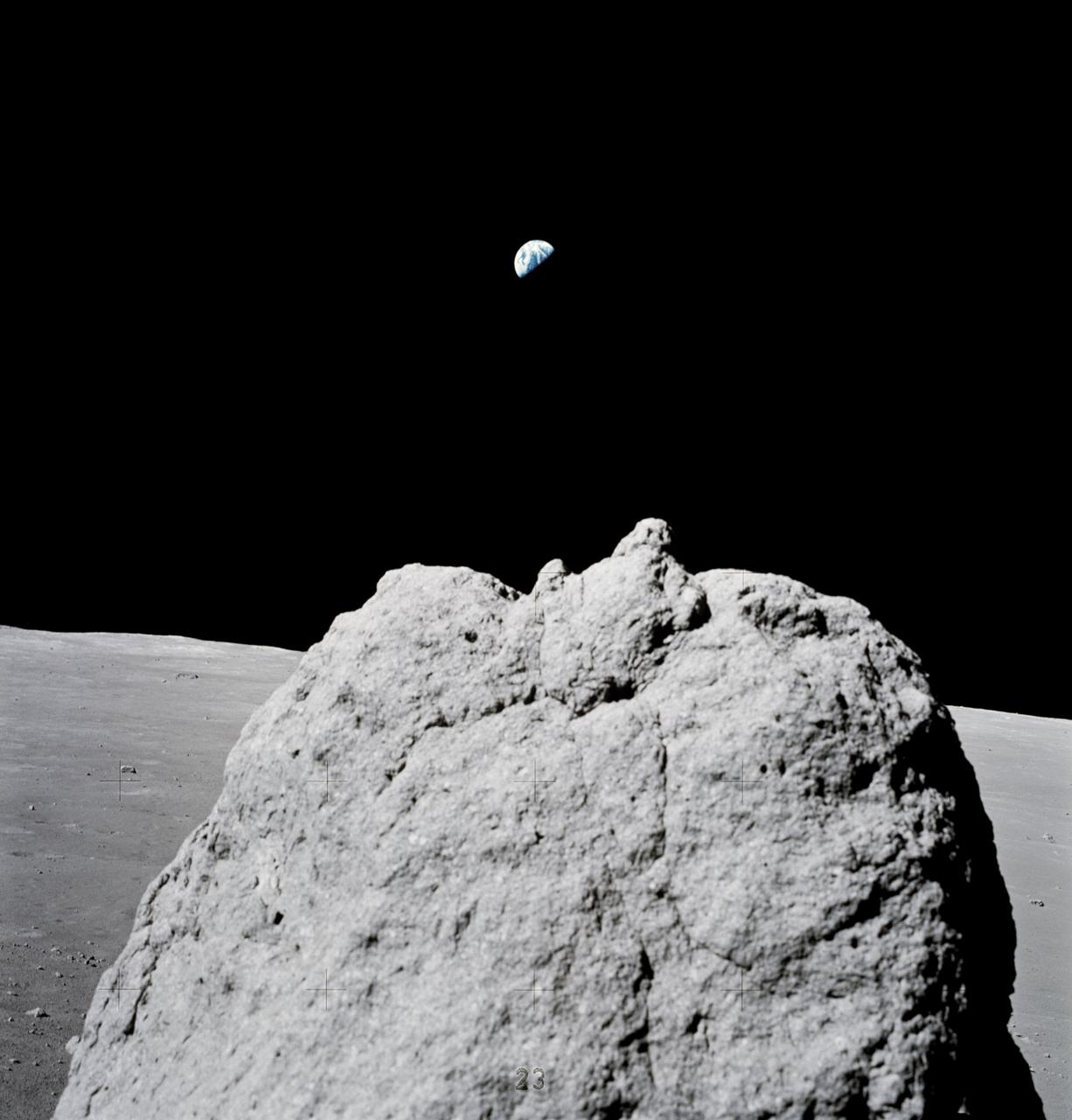 AS17-137-20910 (7-19 Dec. 1972) --- Earth (far distant background) is seen above a large lunar boulder (foreground) on the moon. The photo was taken with a handheld Hasselblad camera by the last two moon walkers in the Apollo Program. While astronauts Eugene A. Cernan, commander; and Harrison H. Schmitt, lunar module pilot, descended in the Lunar Module (LM) "Challenger" to explore the Taurus-Littrow region of the moon, astronaut Ronald E. Evans, command module pilot, remained with the Command and Service Modules (CSM) "America" in lunar orbit.