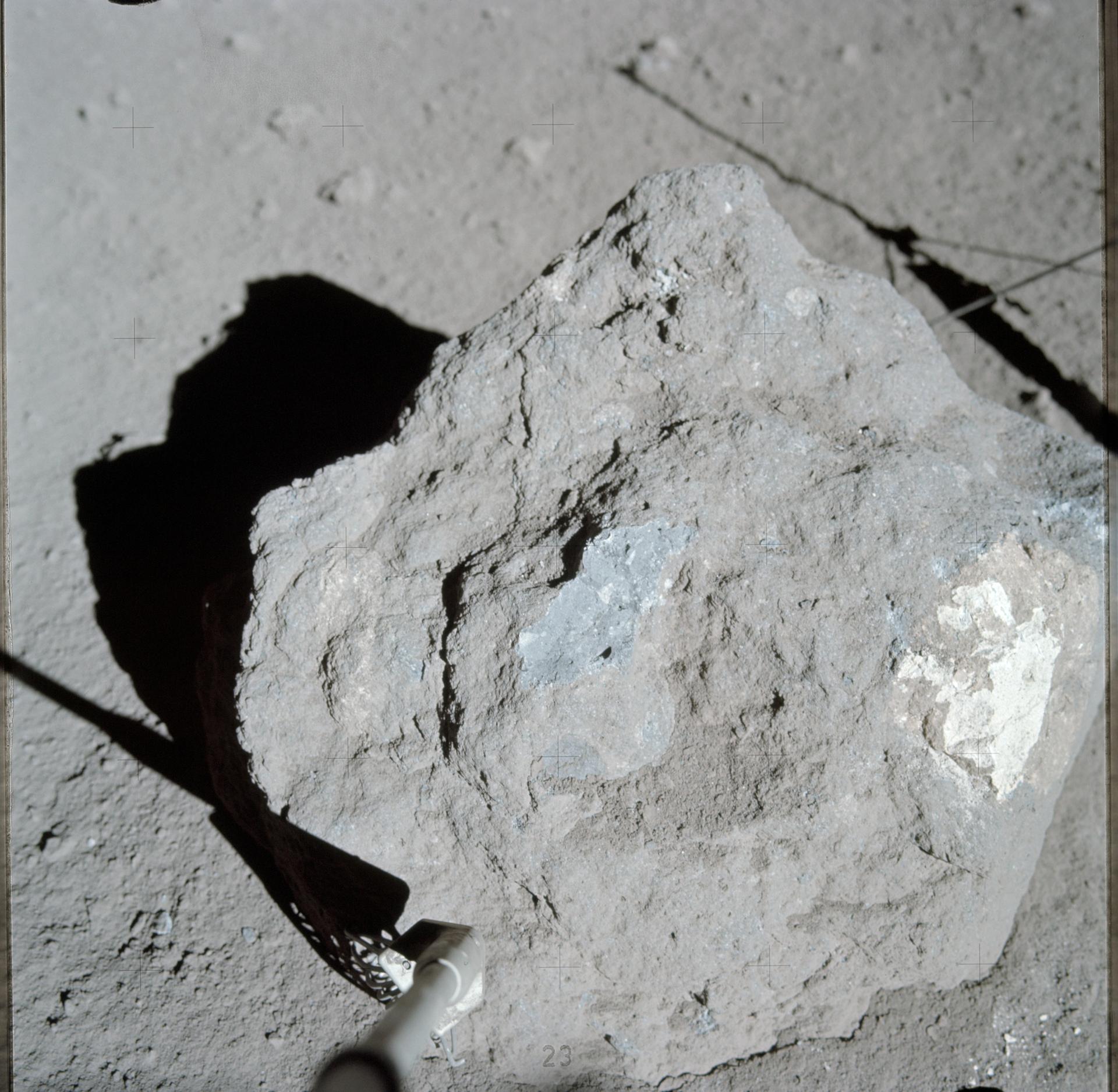 A close-up view of a large grey Moon rock on the lunar surface.