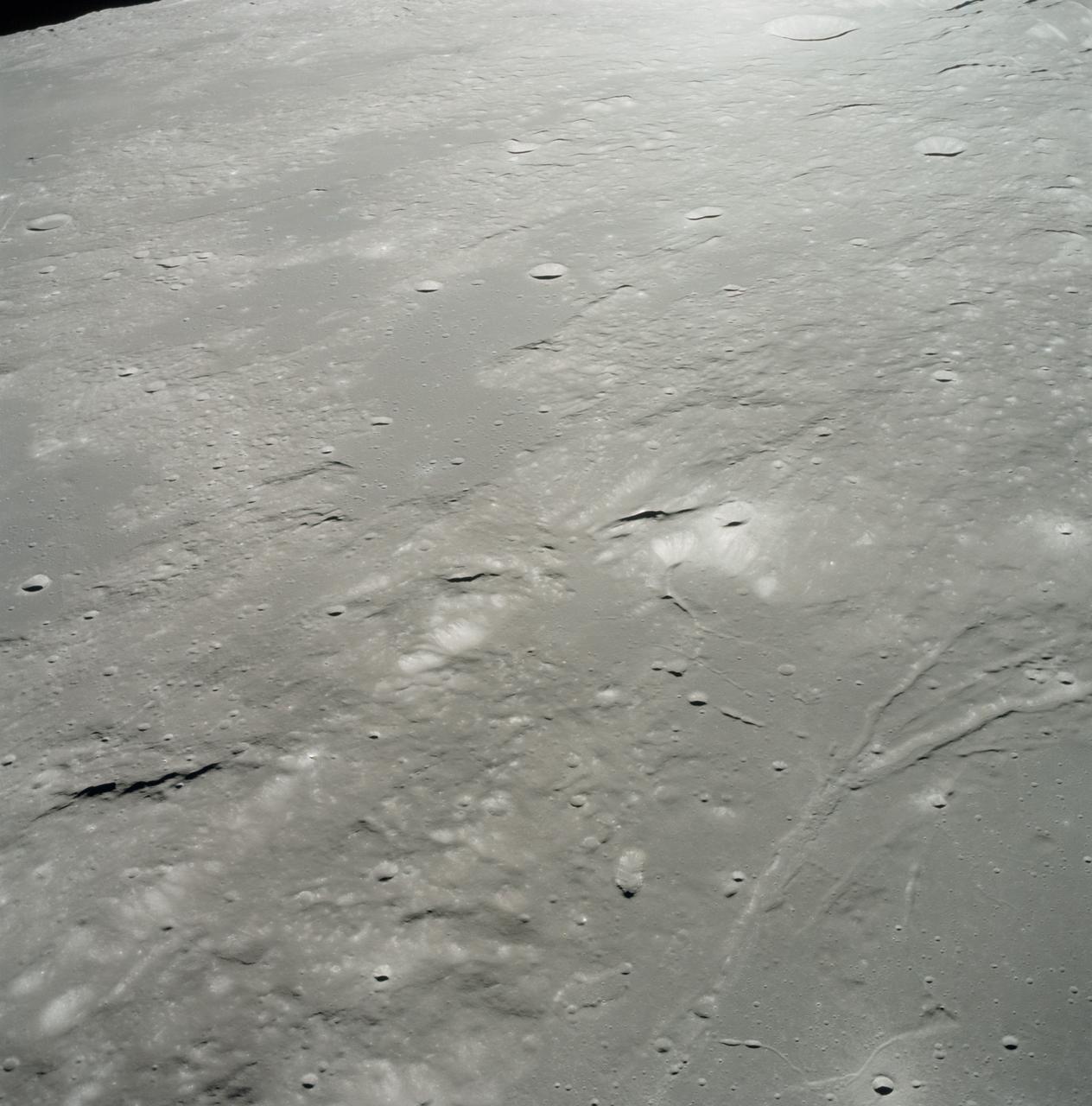 AS17-153-23572 (15 Dec. 1972) --- An oblique view of the Sulpicius Gallus region on the southwestern edge of the Sea of Serenity looking westward across the Haemus Mountains, as photographed from the Apollo 17 Command and Service Modules during its 65th revolution of the moon. This photograph shows the slight orange cast which was identified by astronaut Ronald E. Evans, command module pilot. The region shown in the picture is about 600 kilometers (360 statute miles) west across Mare Serentatis from the Taurus-Littrow landing site where scientist-astronaut Harrison H. "Jack" Schmitt, lunar module pilot, discovered an orange soil sample composed of fine glass particles rich in iron and titanium. North is toward the right. Rima Sulpicius Gallus is the lunar trench or valley (right foreground) that crosses the edge of the Mare and divides into three branches as it runs to the northwest. The crater Sulpicius Gallus is just off the photograph at the bottom right. Note that several small craters in the dark portion of the picture (east) show a more distinct orange cast. The coordinates of the center of this photograph are about 8.4 degrees east longitude and 19.8 degrees north latitude.