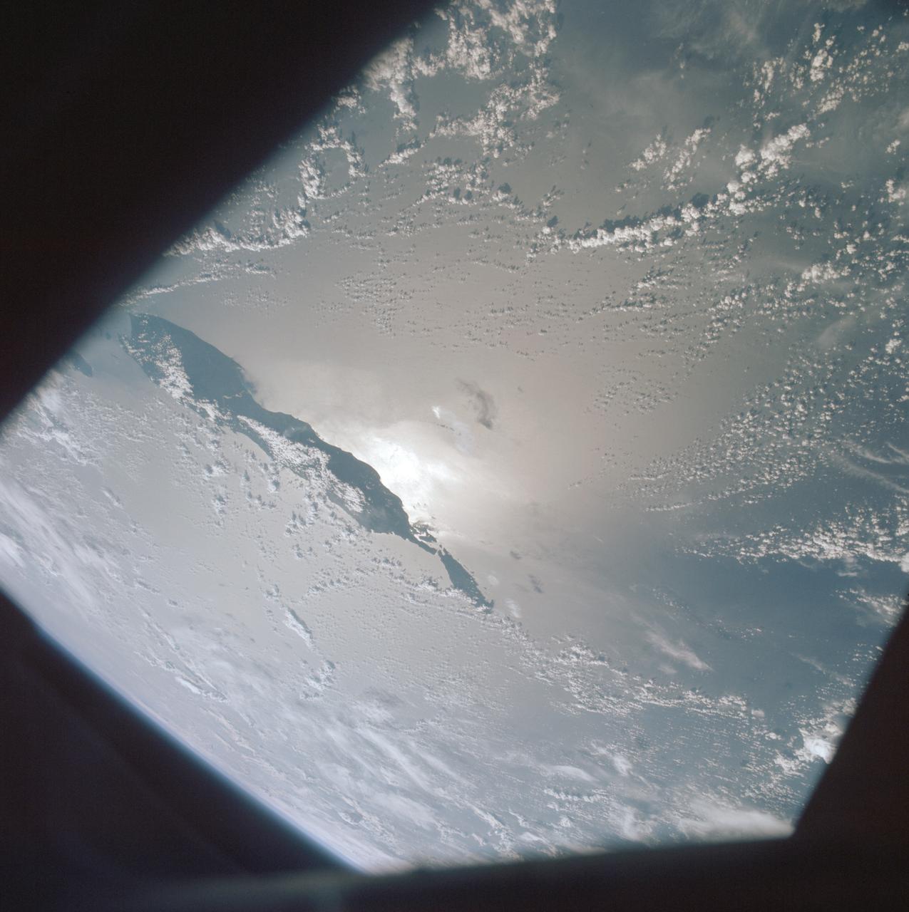 AST-19-1555 (24 July 1975) --- A sunglint in the South Western Pacific Ocean, as photographed from the Apollo spacecraft in Earth orbit during the joint U.S.-USSR Apollo-Soyuz Test Project mission. The island is Bougainville of the Solomon Islands group. The horizon of Earth is in the background. The picture was taken at an altitude of 231 kilometers (143 statute miles), with a 70mm Hasselblad camera using medium-speed Ektachrome QX-807 type film.