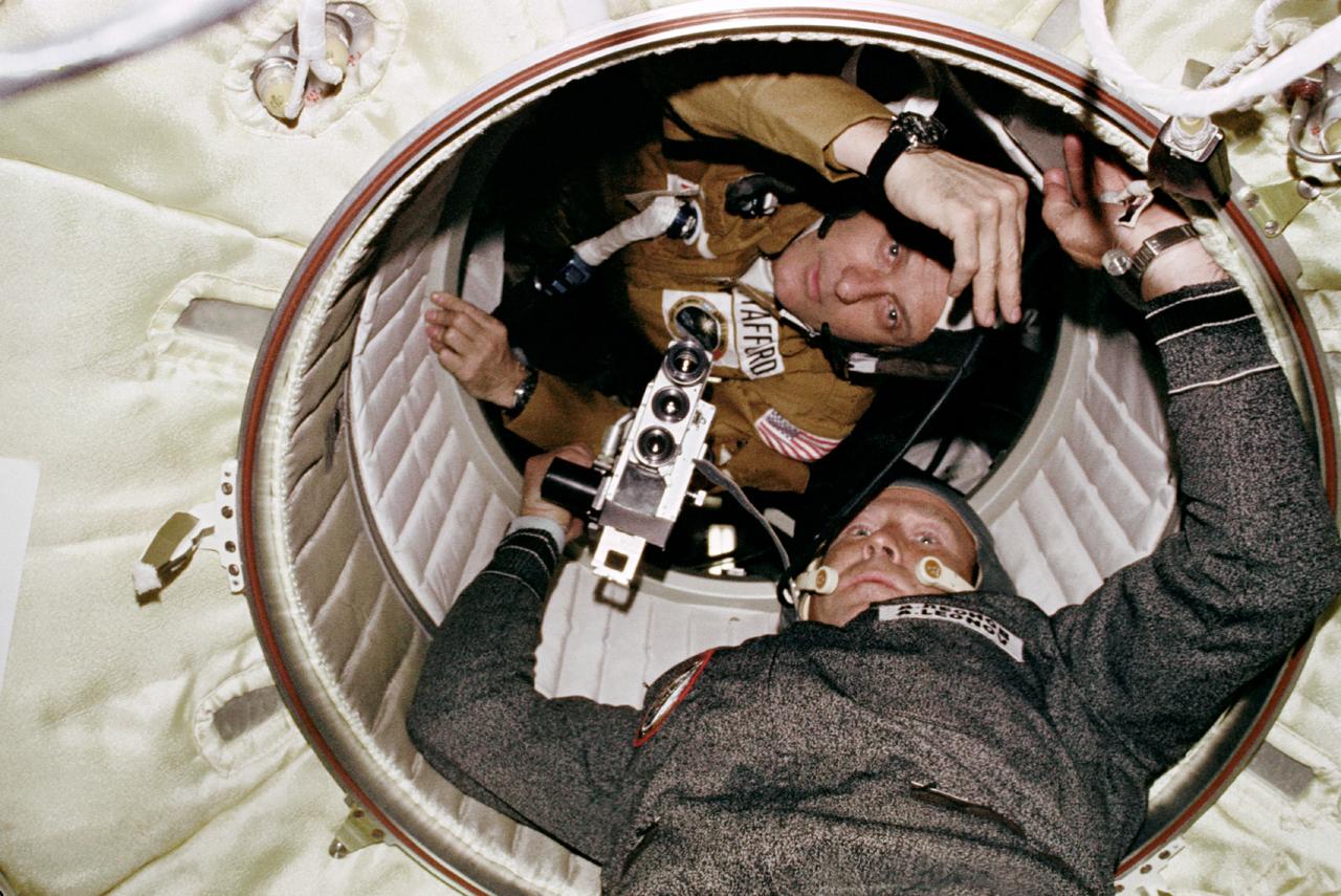 AST-03-191 (17-19 July 1975) --- Astronaut Thomas P. Stafford and cosmonaut Aleksei A. Leonov are seen at the hatchway leading from the Apollo Docking Module (DM) to the Soyuz Orbital Module (OM) during the joint U.S.-USSR Apollo Soyuz Test Project (ASTP) docking mission in Earth orbit. Cosmonaut Leonov is in the OM and astronaut Stafford is in the DM.  Leonov holds a camera. The Apollo crew consisted of astronauts Stafford, commander; Donald K. "Deke" Slayton, docking module pilot; Vance D. Brand, command module pilot.  The Soyuz 19 crew consisted of cosmonauts Leonov, command pilot; and Valeri N. Kubasov, flight engineer.