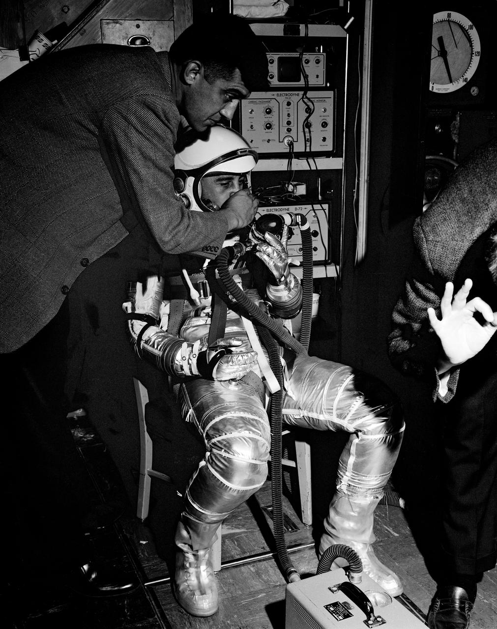 G61-00490 (1961) --- Astronaut Virgil I. (Gus) Grissom, wearing the new Mercury pressure suit, is preparing for centrifuge training. He is receiving assistance in adjusting the breathing apparatus which is attached to a data recording device at his feet. Assisting him is Dr. Jackson. Photo credit: NASA