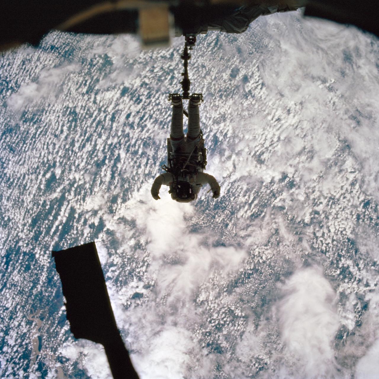 ISS002-707-057 (22 April 2001) --- 70-mm frame. STS-100 EVA crewmember Chris Hadfield in dark silhouette - shadowed by the ISS on work/foot pedestal platform for the Remote Manipulator System (RMS) over a 90% cloud covered earth background.  A small segment of an unidentified river is in the lower left corner. 22 April 2001 Altitude 208 nautical miles